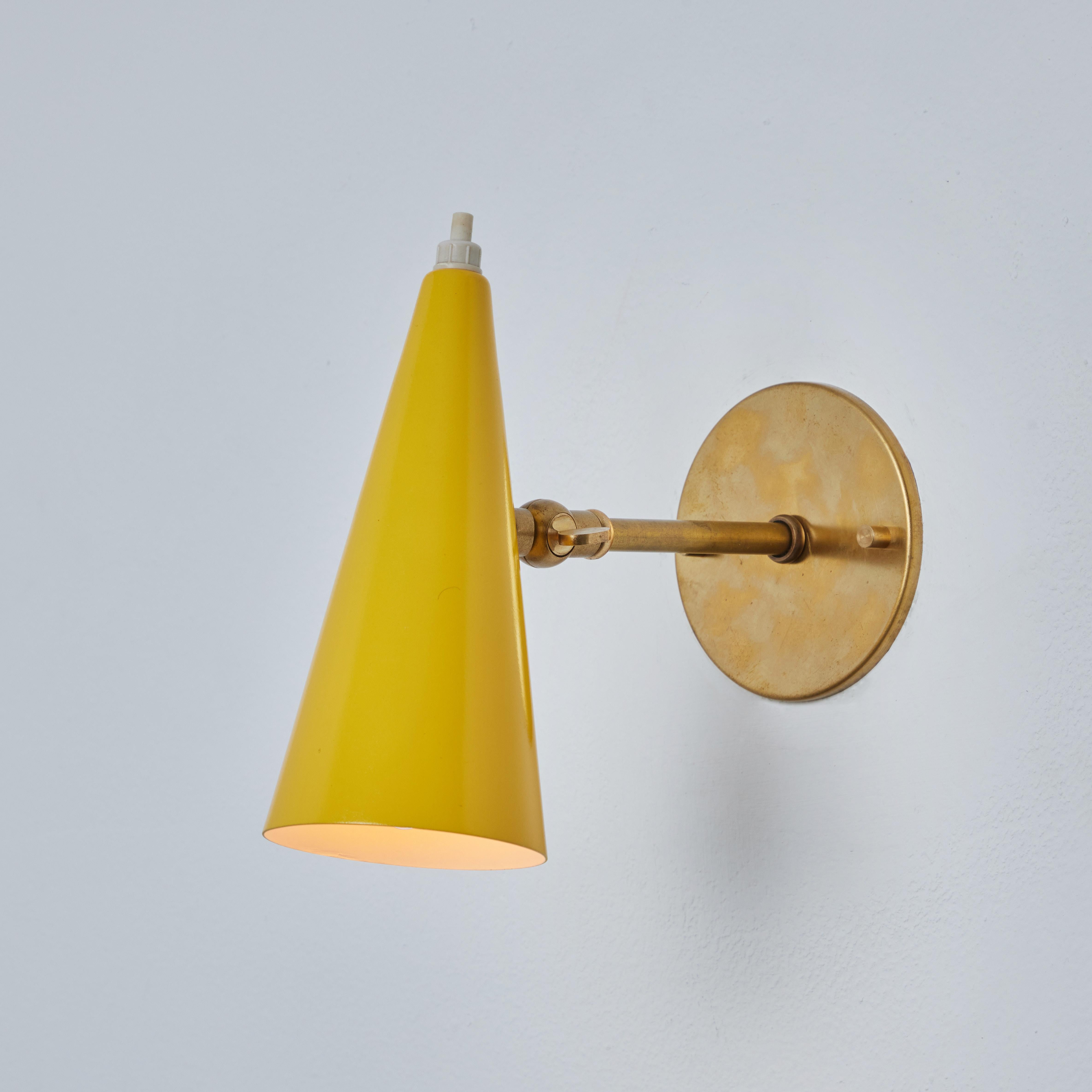 1960s Stilux Milano yellow and brass conical wall lamp. This quintessentially midcentury Italian wall lamp is executed in an adjustable conical yellow painted metal shade with white-painted interior mounted on a patinated brass arm in very good