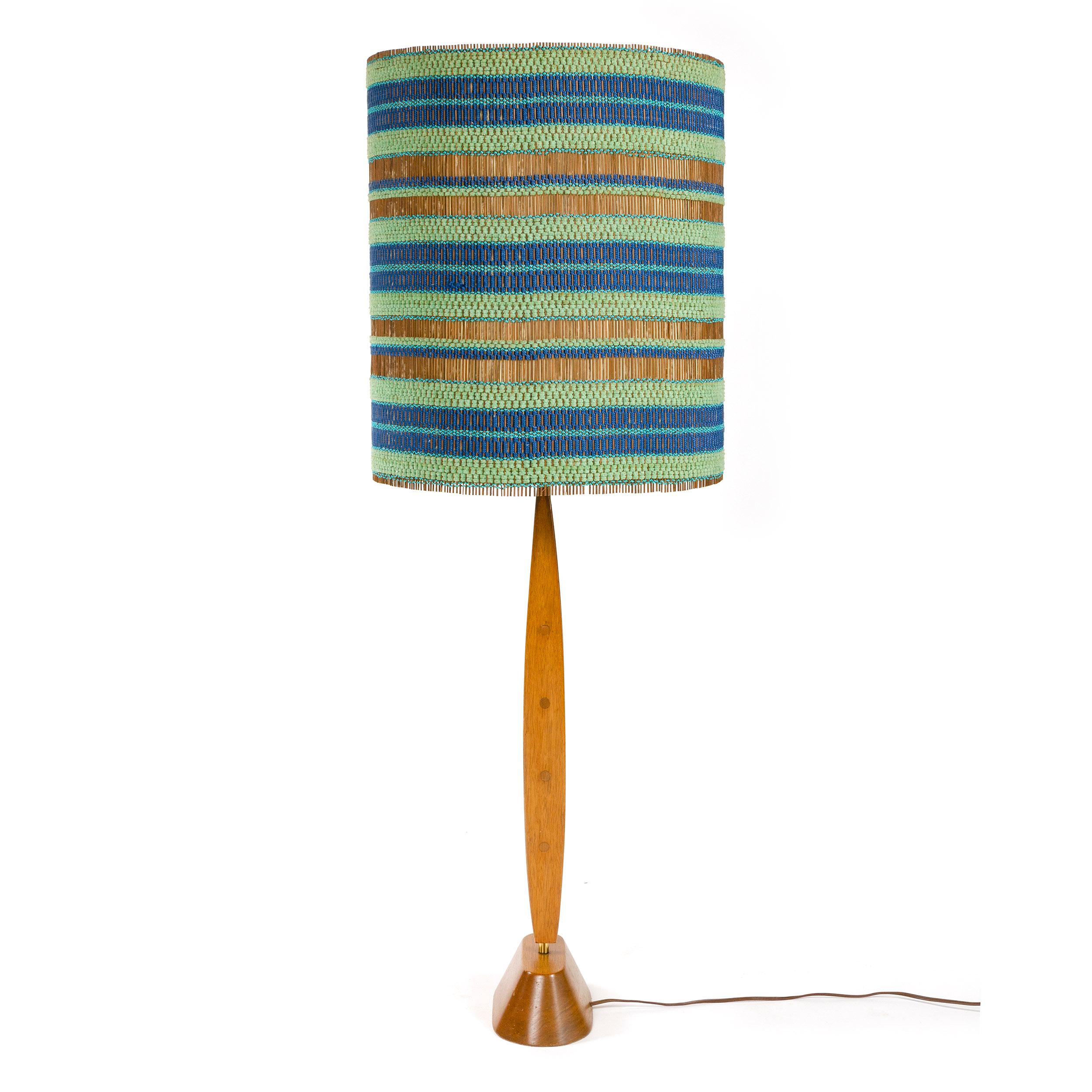 A mahogany and brass table lamp with decorative stone tiles paired with a matchstick chenille shade, woven with blue and turquoise threads.