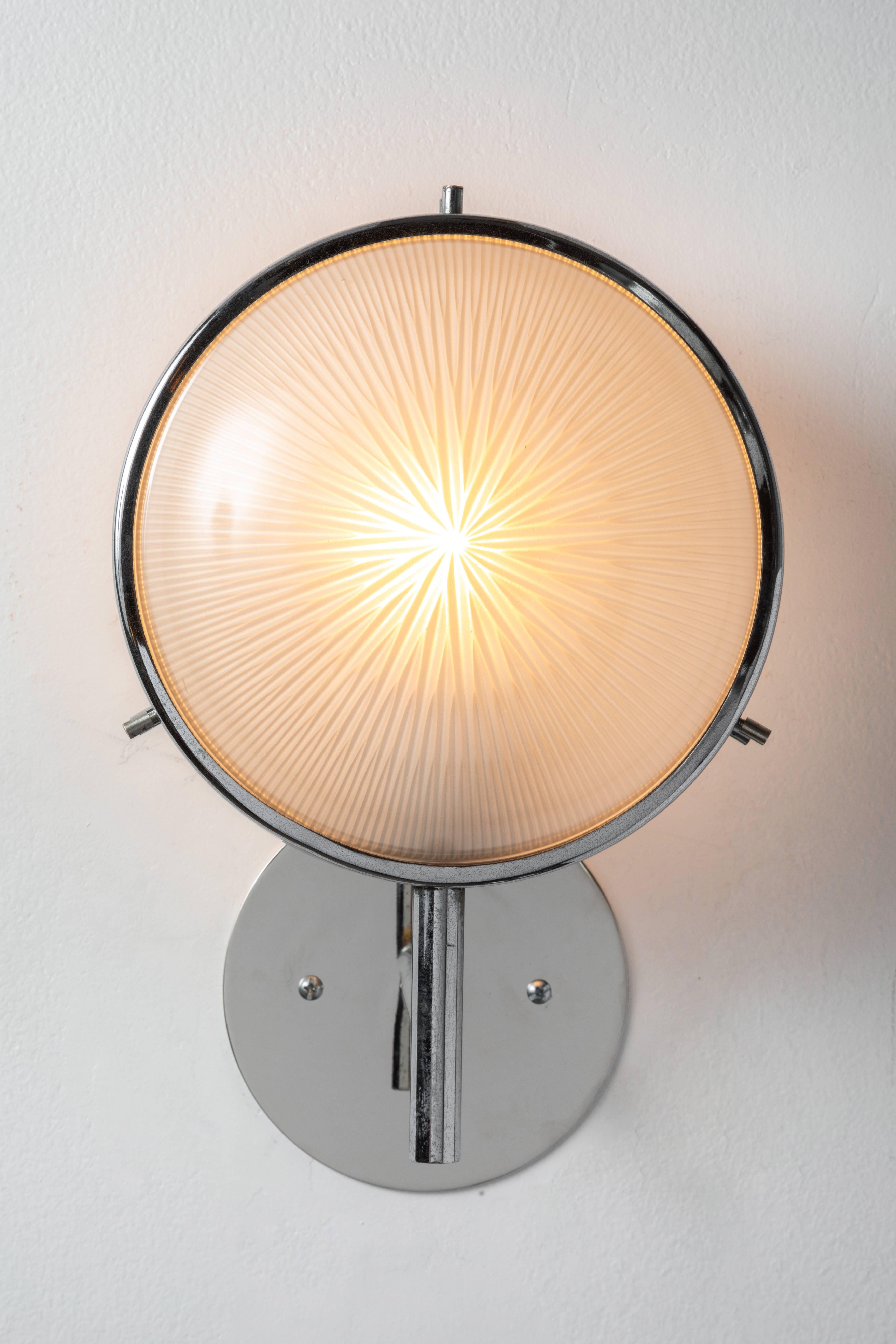 1960s Studio B.B.P.R glass and metal sconce. Executed in polished nickel, painted metal and pressed glass. Lamp freely rotates left and right for a flexible variety of lighting configurations. Professionally rewired for US electrical accommodates a