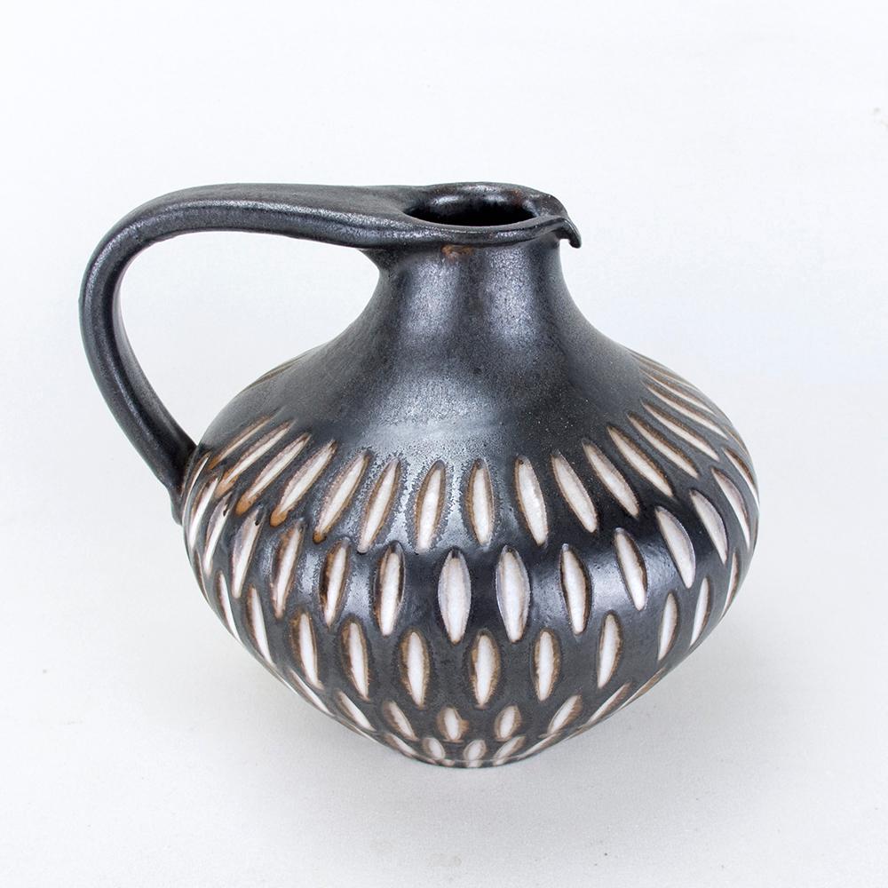 Ceramic jug in a dark matt glaze with an incised creamy white pattern. The jug was made in the 1960s in the German pottery workshop of Wilhelm & Elly Kuch. The pottery's logo is embossed on the base.
Very good condition & 100% original condition.