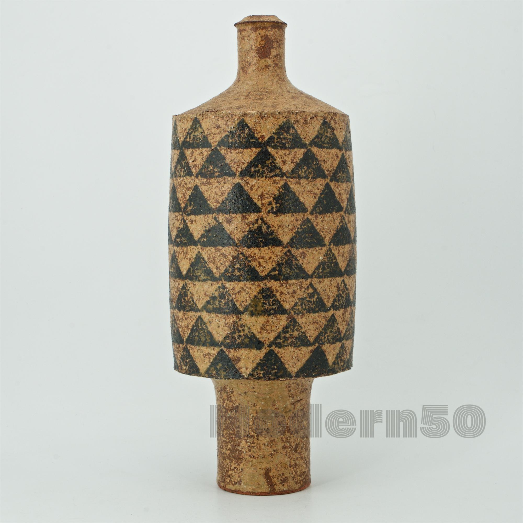 Appears to be a highly textured turned salt fired stoneware centerpiece vase/bottle, with nice stenciled or painted slip geometric triangle pattern completely around the body. No makers markings that we can find.