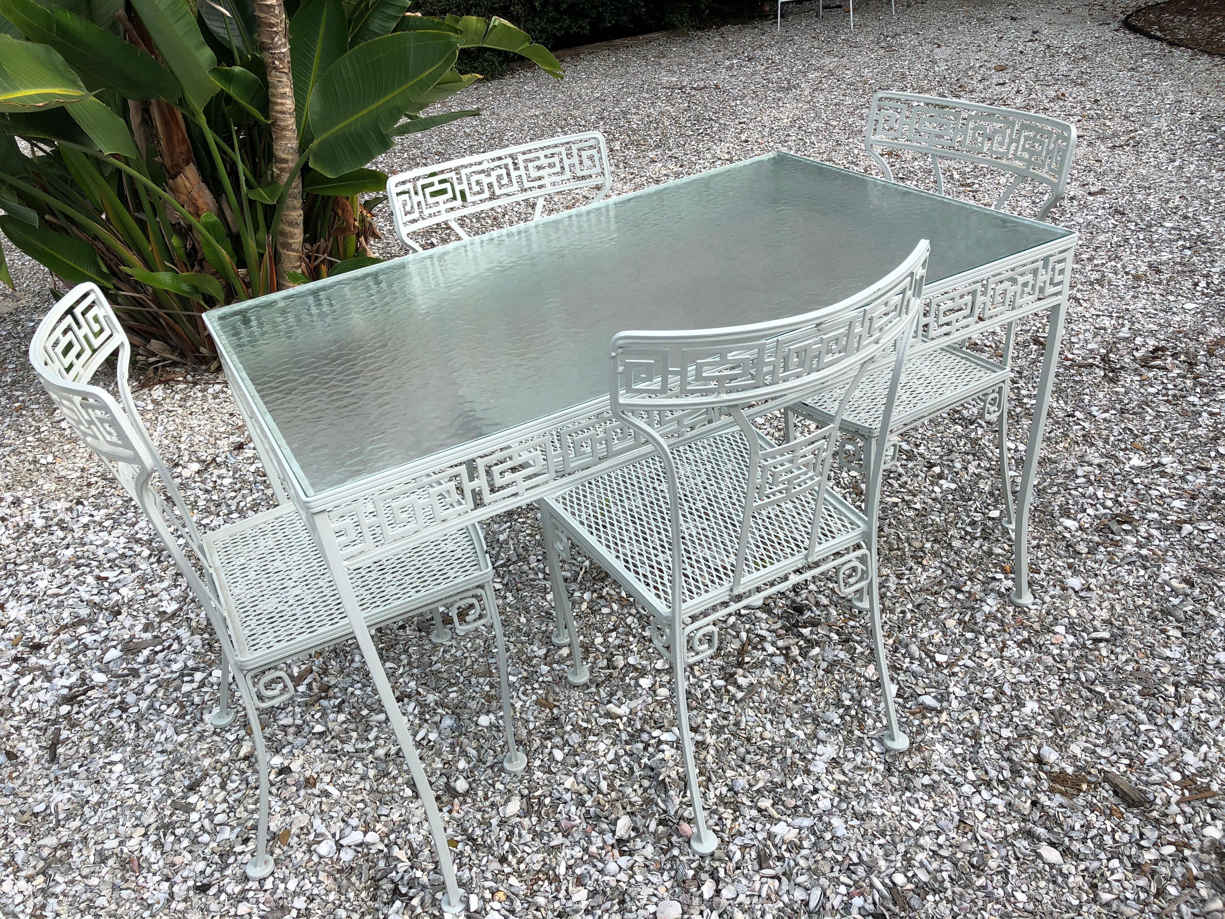 Rarely do you find this table and even more rare is finding it with its original water reflection glass so popular during the 1960s patio pool epiphany. Stunning powder coated white Greek Key pattern table and four matching chairs, powder coated in