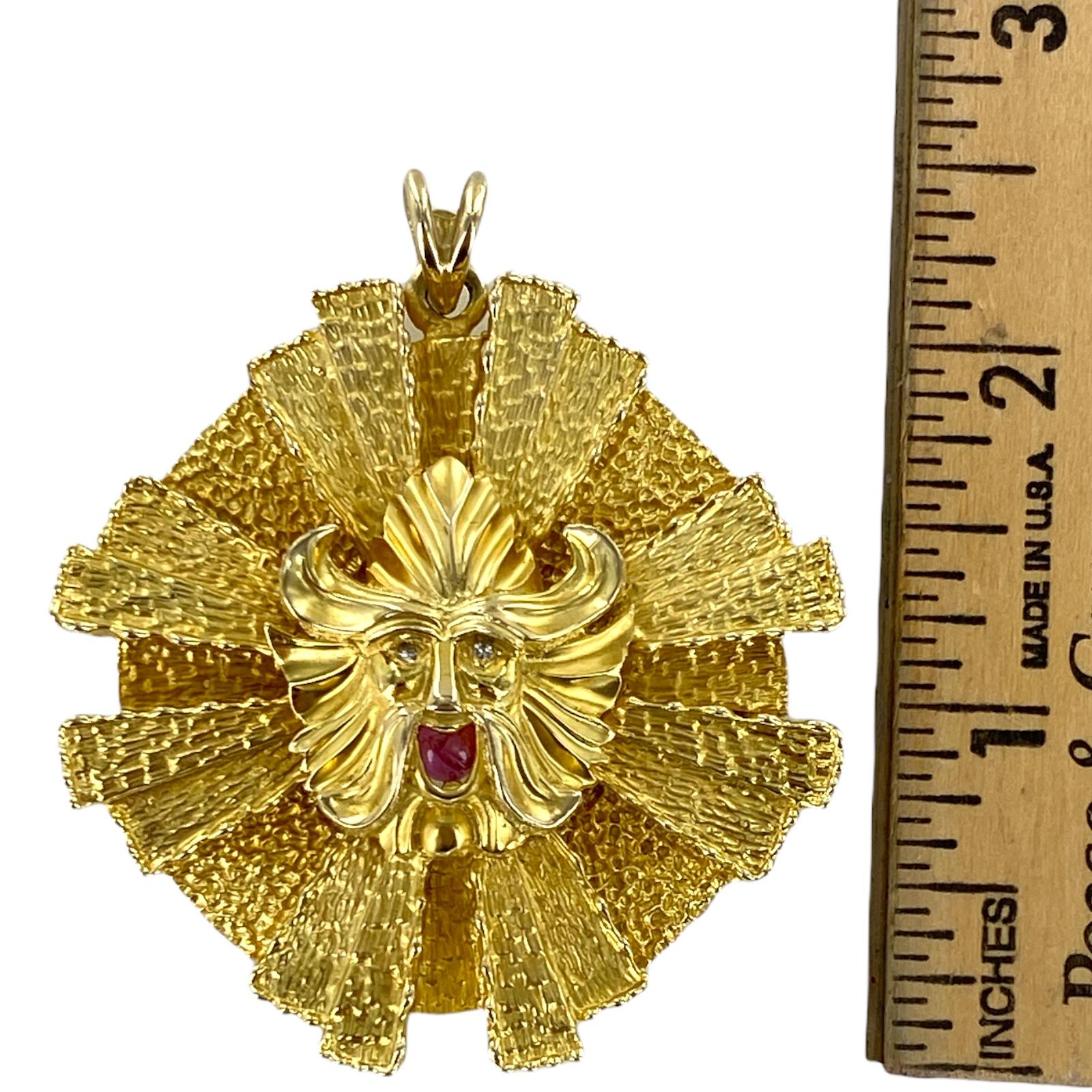 Handcrafted sunburst pendant fashioned in solid 14 karat yellow gold. The textured gold pendant features  a Viking with 2 diamond eyes and a cabochon ruby mouth. The pendant measures 2.25 inches in diameter. 