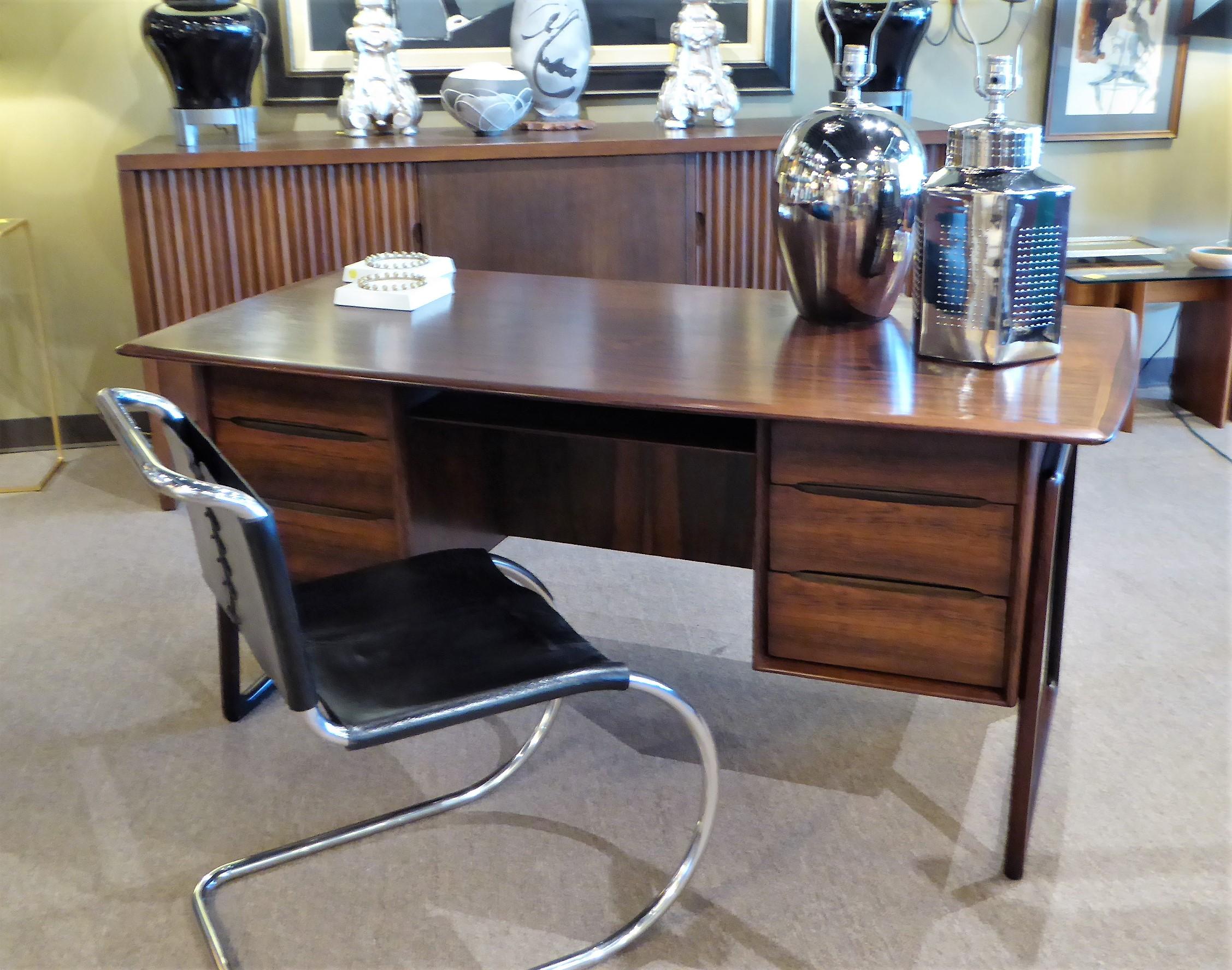 Fine and beautiful rosewood desk designed by Svend Aage Madsen in Denmark. With a floating style top over three drawers left and right and a pass through shelf, front to back. The back side with a deep shelf for books or whatnot. Supported on