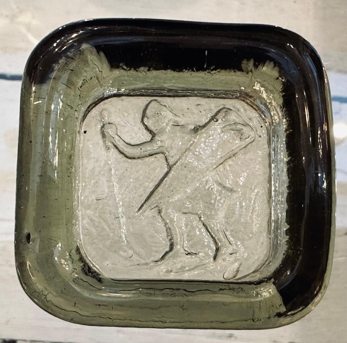 1960s Small Swedish paperweight, ashtray or trinket dish which is made from a thick piece of square coloured light olive glass. The warrior with a sword & shield design is pressed into the base of the glass to form the indented dish shape. The dish