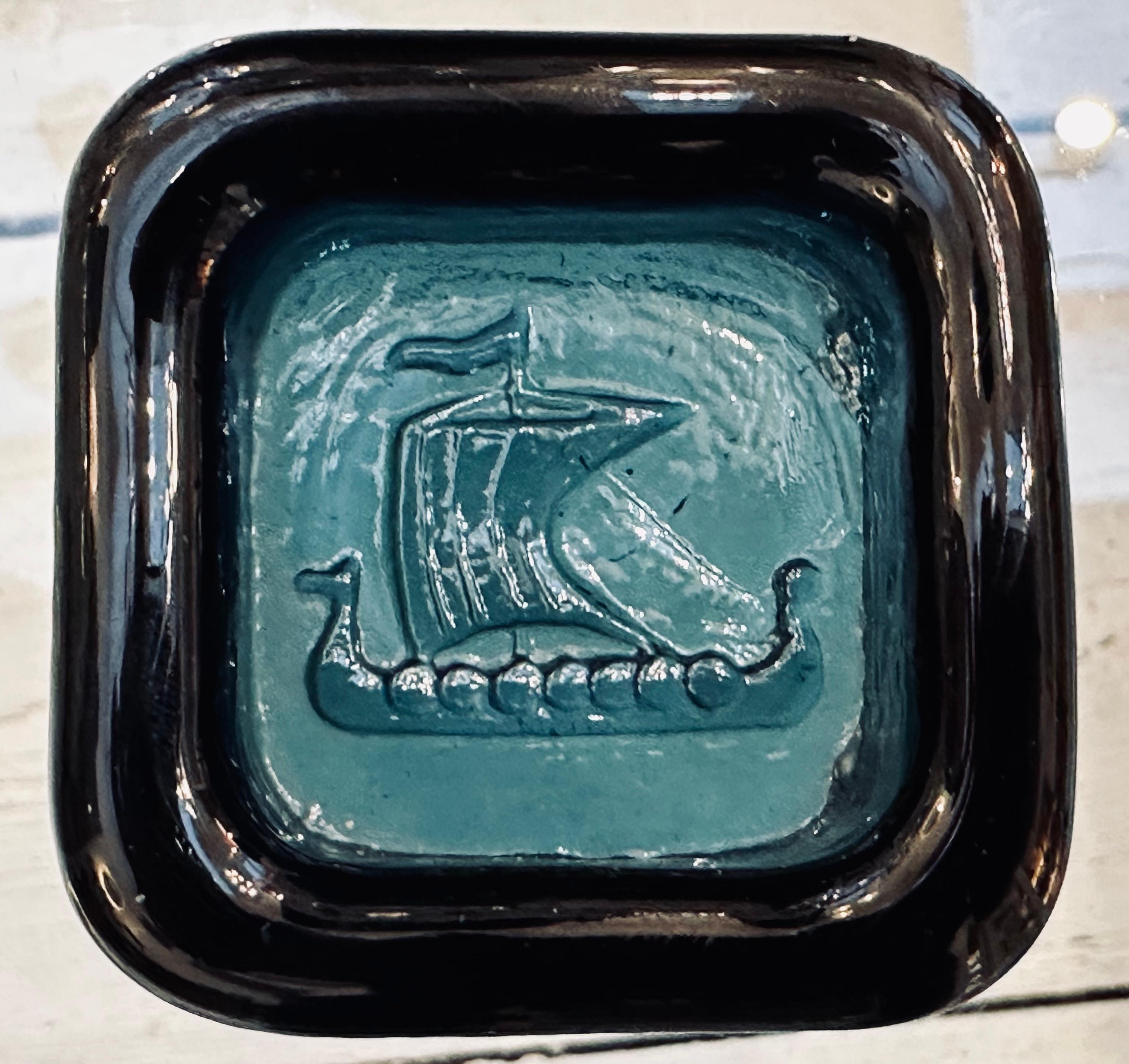 1960er Jahre Kleiner schwedischer Briefbeschwerer, Aschenbecher oder Schmuckschale aus einem dicken Stück quadratischem, dunkelgrünem Glas. Das Wikingerschiff-Motiv wird in den Boden des Glases gepresst, um die eingedrückte Schalenform zu bilden.
