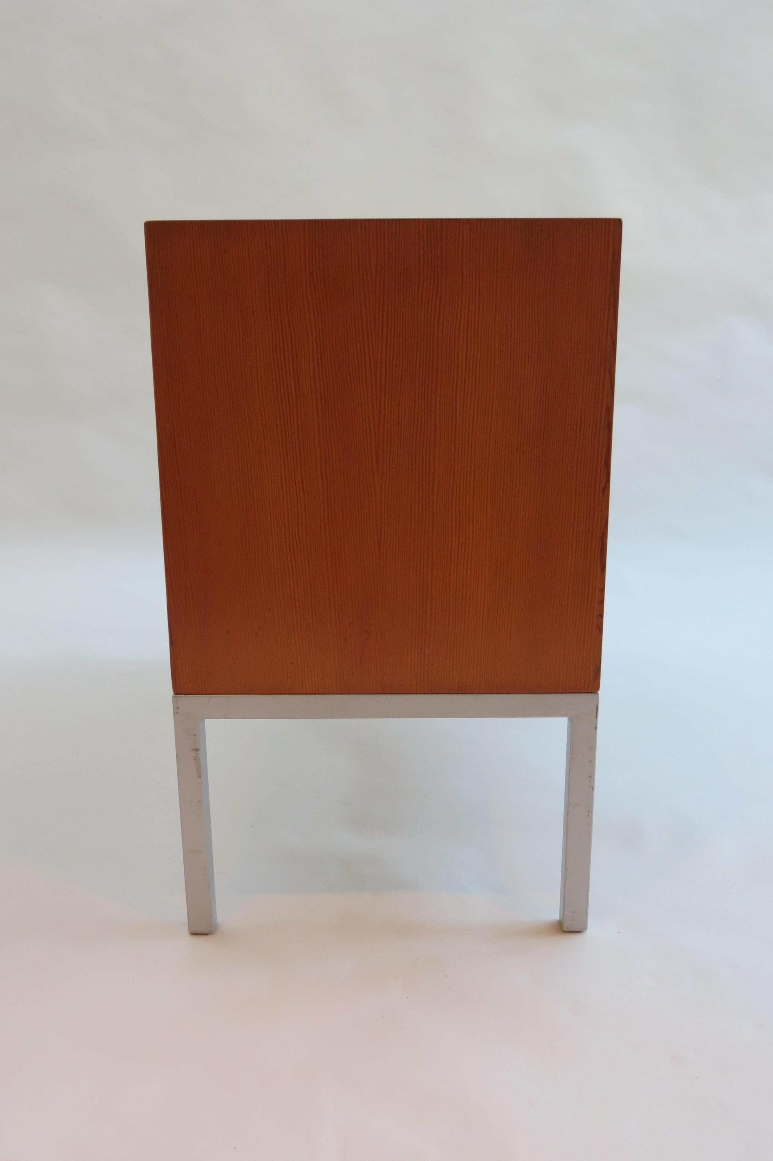 This is a good quality cabinet from the 1960s. The cabinet has an Oregon pine veneer case and painted steel base. The upright shelving dividers can be adjusted to make the openings either wider or narrower. Nice quality with mitred corners. The