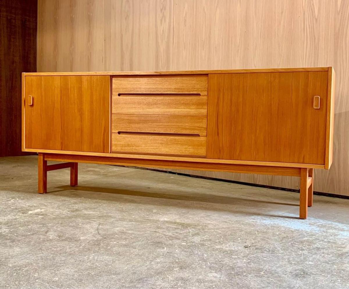 Fresh from a complete restoration, we're excited to present this beautiful teak credenza designed by Nils Jonsson for Troeds in the 1960s. It boasts a pair of smooth sliding doors revealing adjustable shelves inside, alongside a set of solid wood,
