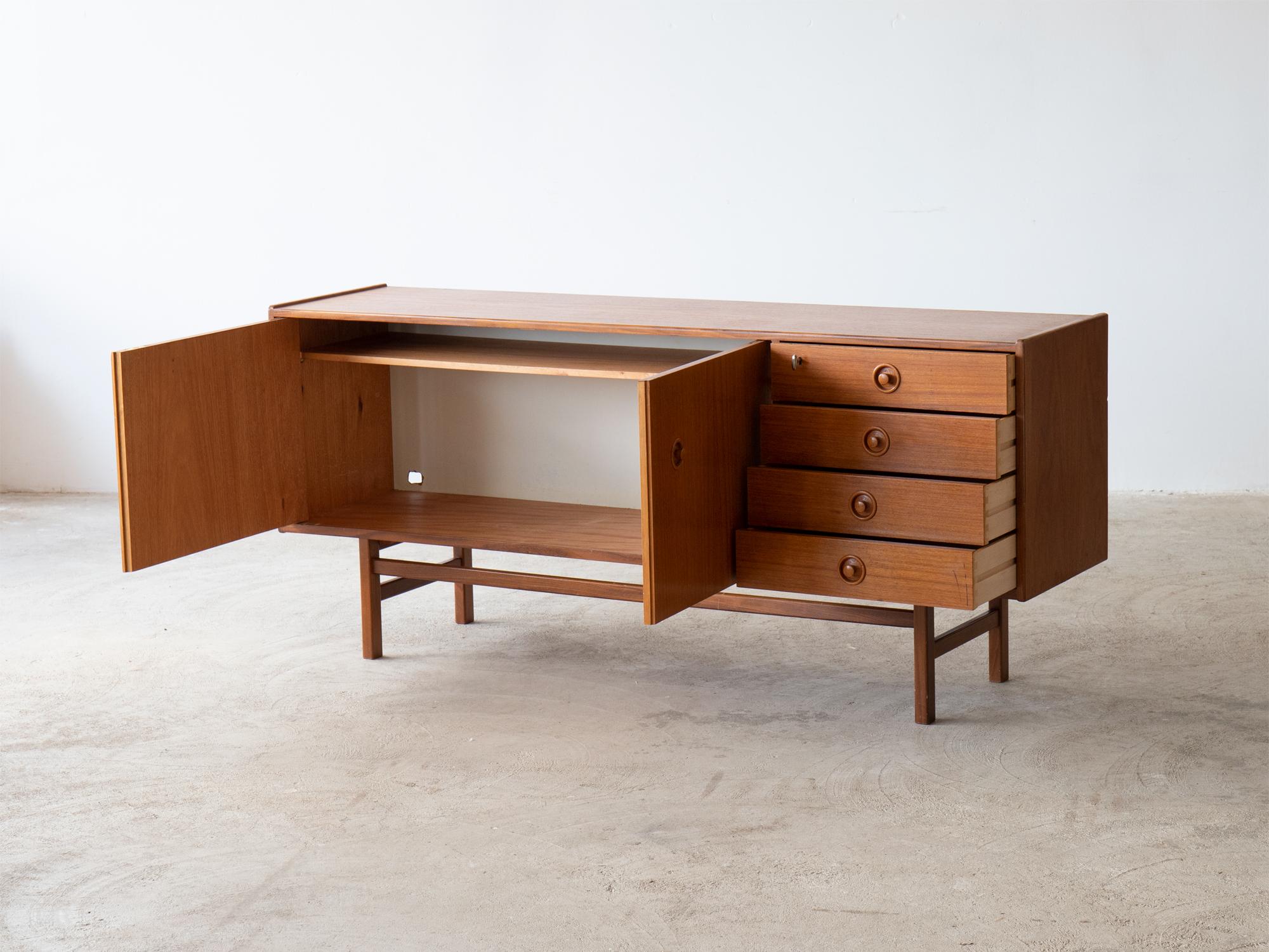 A mid-century teak & teak-veneered sideboard.

Swedish, circa 1960.

Four vertical drawers, the top partitioned, sit beside a two-door cupboard with internal shelving.

In good order. Structurally sound with working locks & keys. Cosmetic wear