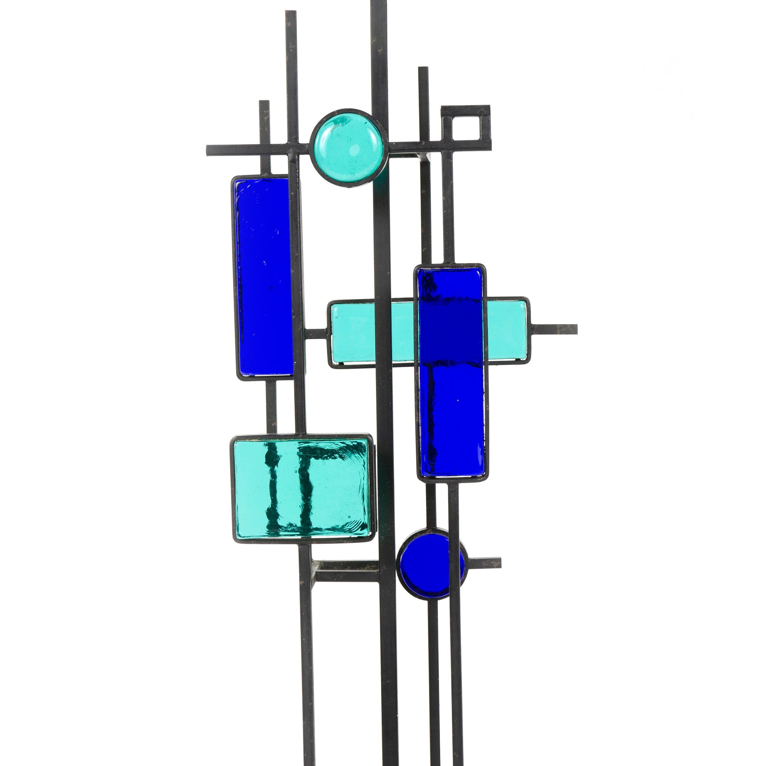 Une paire de hautes lampes de table ou de sol en fer forgé noir et en verre. Diverses pièces de verre épais vert et bleu de formes géométriques encadrées de fer forgé noir et suspendues à des tiges métalliques fines et carrées au-dessus d'une base