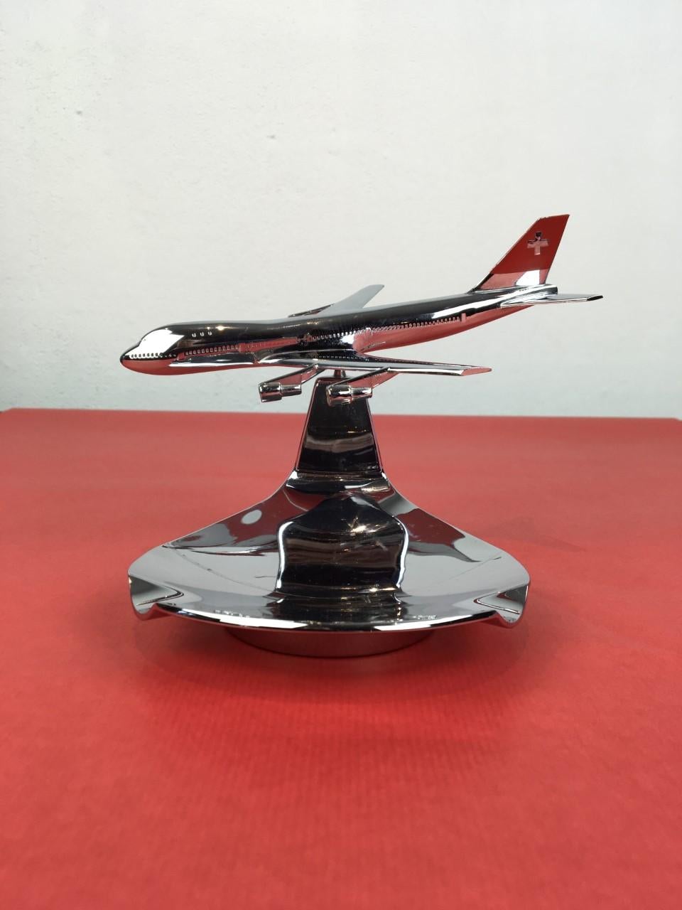 1960s chrome ashtray for Swissair. 
This ashtray has an airplane on top which can be turned in a position of choice by the ball joint. 
It's a Swissair DC8 aeroplane. 
This vintage chrome ashtray is marked under: Made in Switserland - Buhler