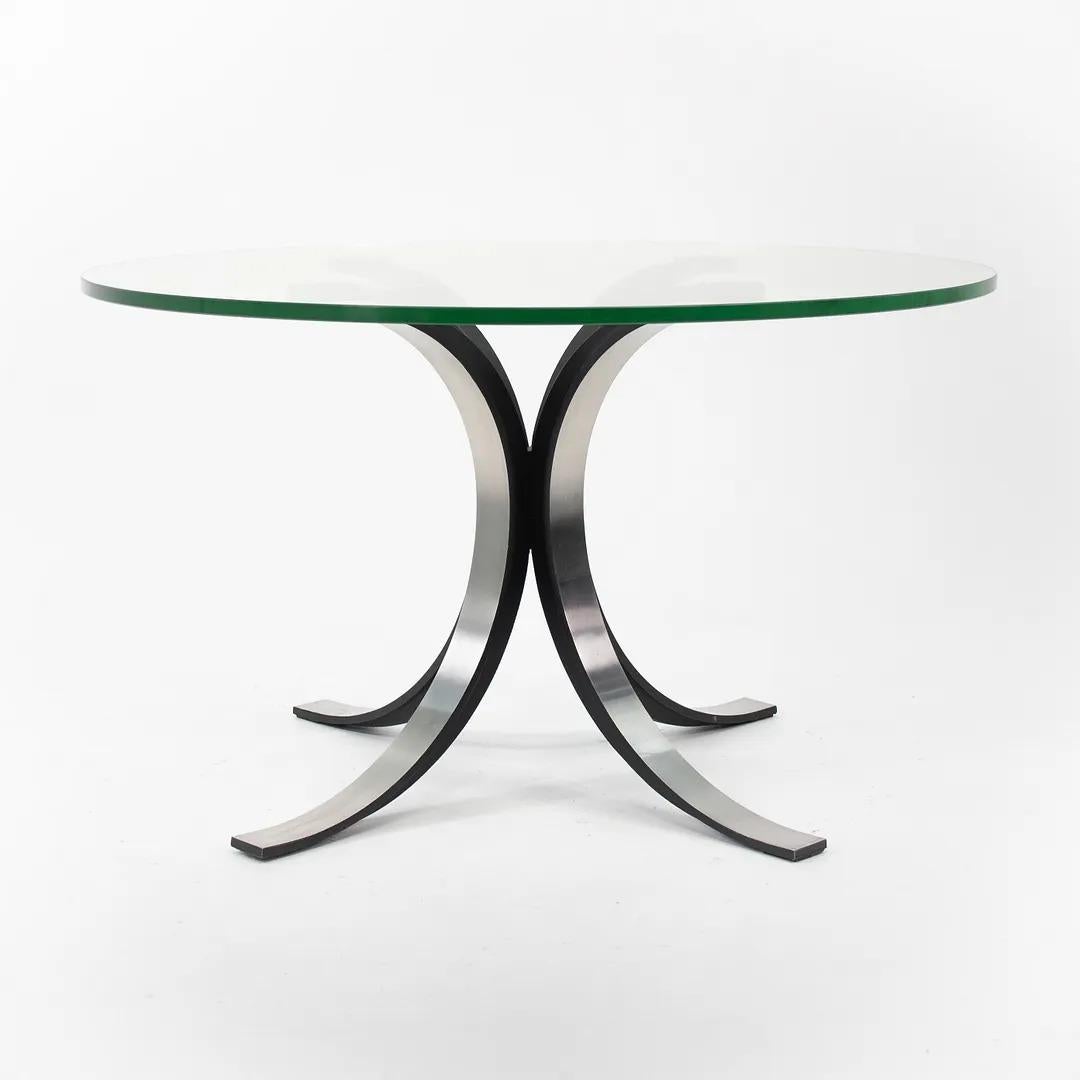 This is a T69 dining table, originally designed by Osvaldo Borsani and Eugenio Gerli for Tecno Italia in 1963. The base is constructed of die-cast aluminum with applied black lacquer. It also has a thick glass top. The table was manufactured in