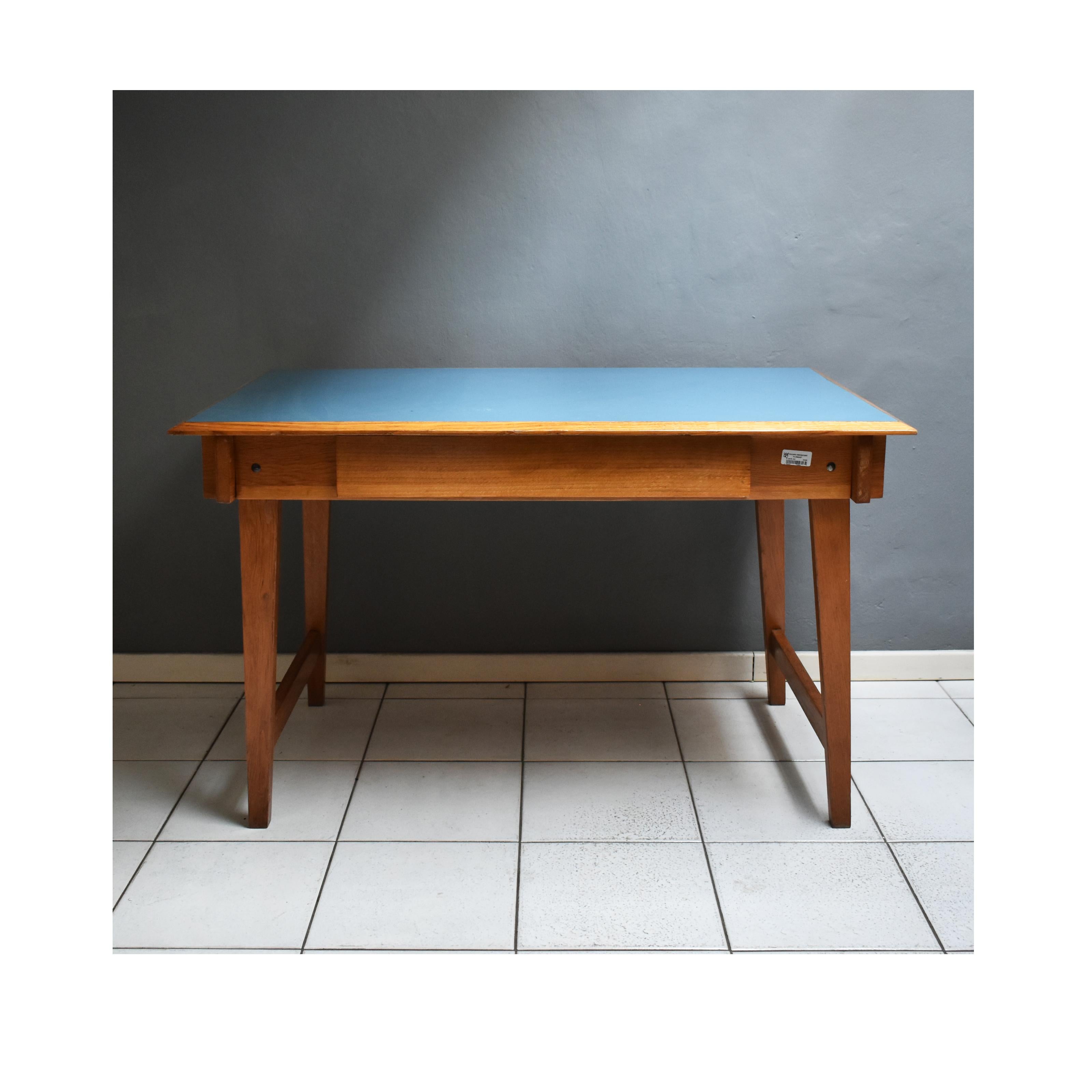 1960s desk, Italian manufacture in wood and light blue formica top.
It is a mid-century table/writing desk.
The desk has a rectangular structure with a central drawer in wood.
The table has a label that showing the provenance: University of R.