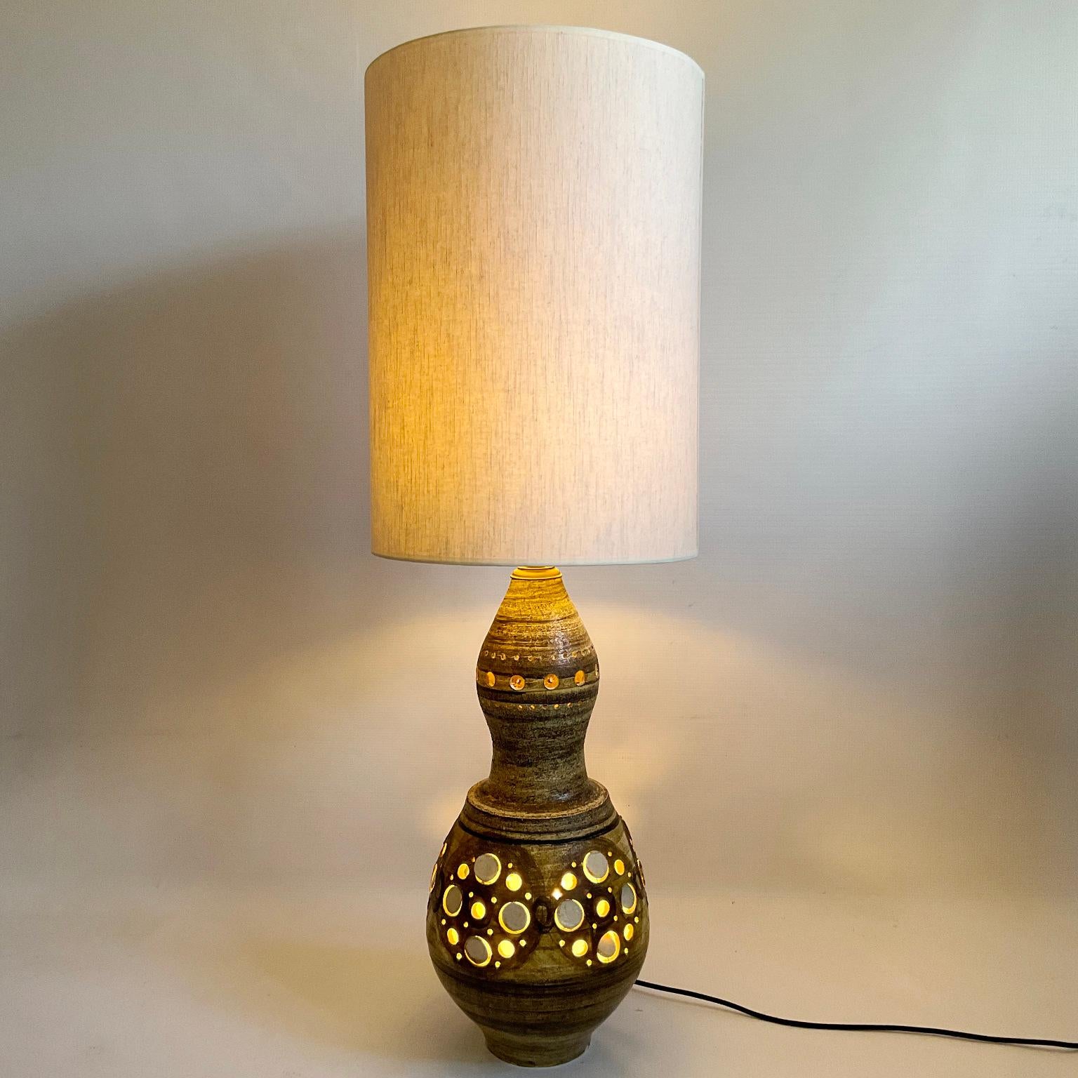 This large table lamp or floor lamp from the 1960s is a fine example of craftsmanship, made of clay and painted by hand by the artist Georges Pelletier, a French ceramist well known to collectors.
This lamp has two lights, one inside, highlighting