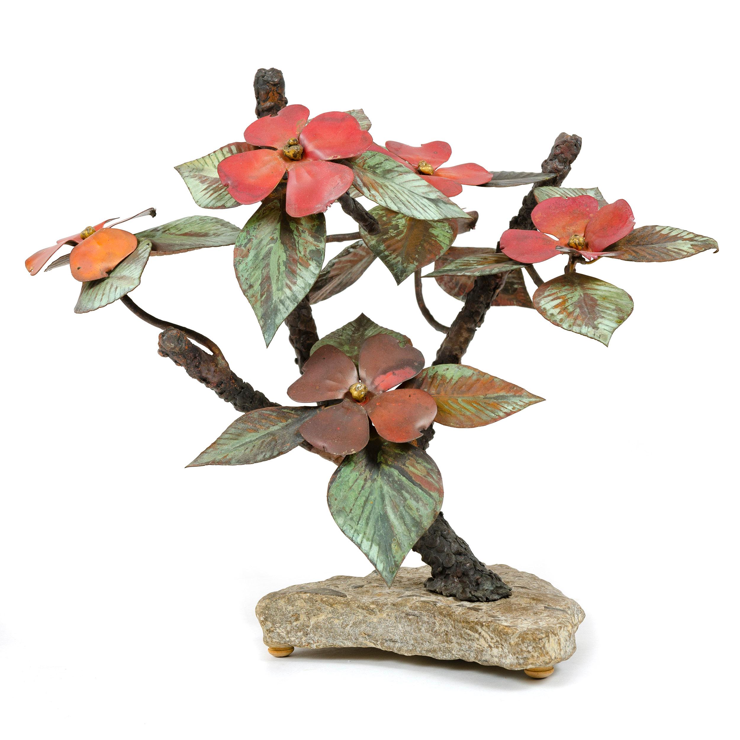 From Steck’s 'Windswept' series, this tabletop sculpture exhibits thick, textured limbs with thinner branches displaying patinated leaves and numerous four petal flowers of an oxidized, cardinal red hue the whole set on a rugged, light color