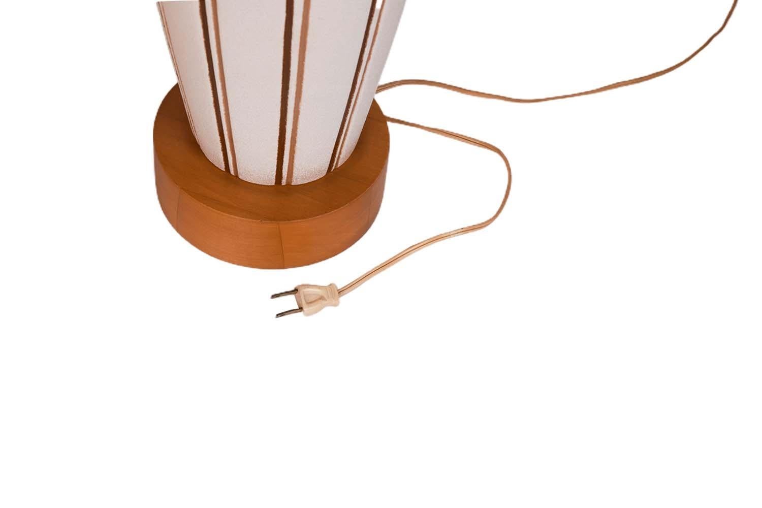 A beautiful pair of vintage Danish Modern style pottery table lamps with original drum shades, circa 1960s. They feature white ceramic urn or bottle form bases with brown and tan vertical stripes on solid walnut stands and turned walnut necks. The