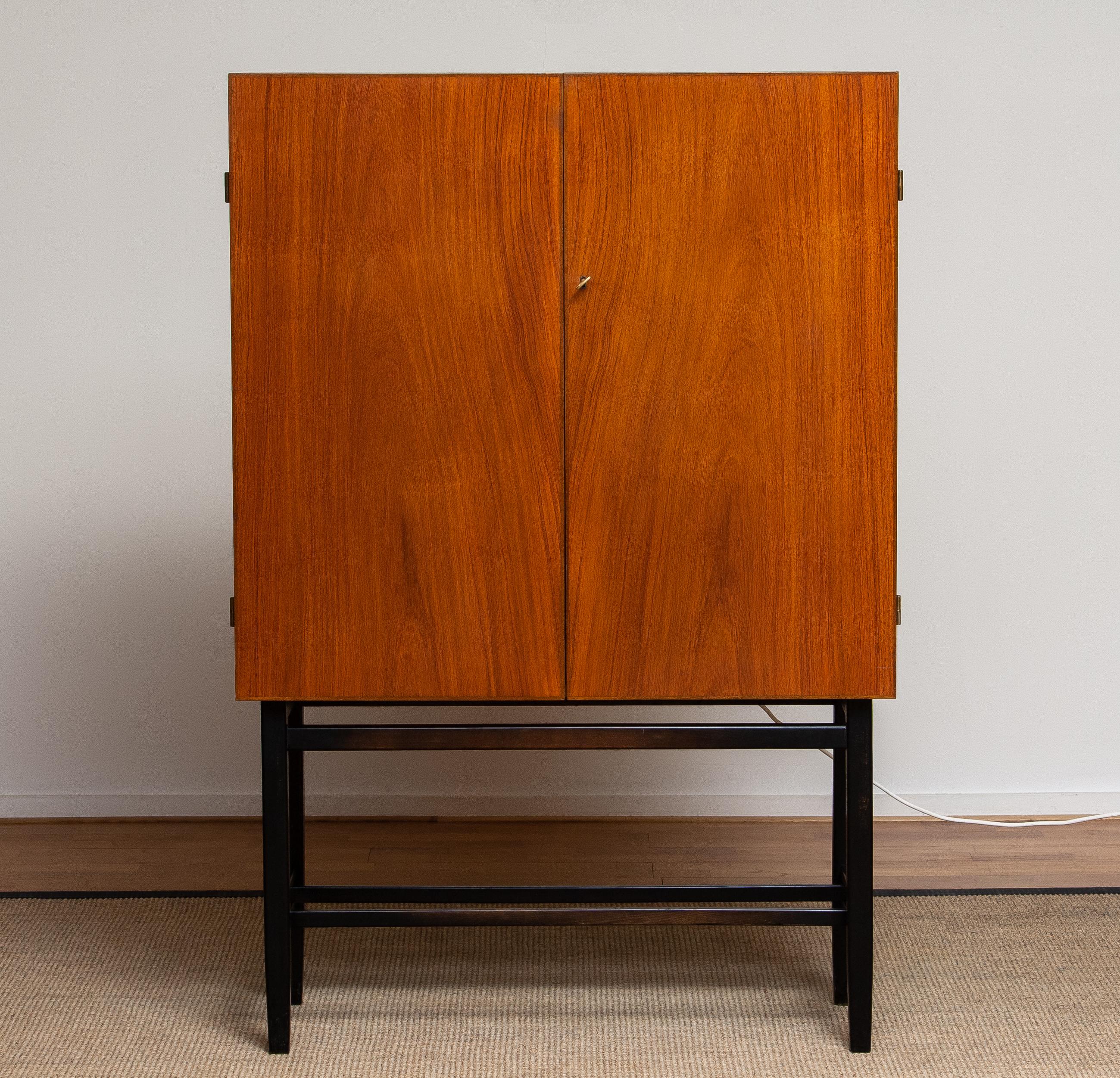 Extremely beautiful and complete dry bar or drinks cabinet made by Förenade Möbelfabrikerna Linköping in 1965.
Inside the dry bar cabinet, there are three teak drawers with green velvet inside and on top a mirror shelf. The back of the cabinet is