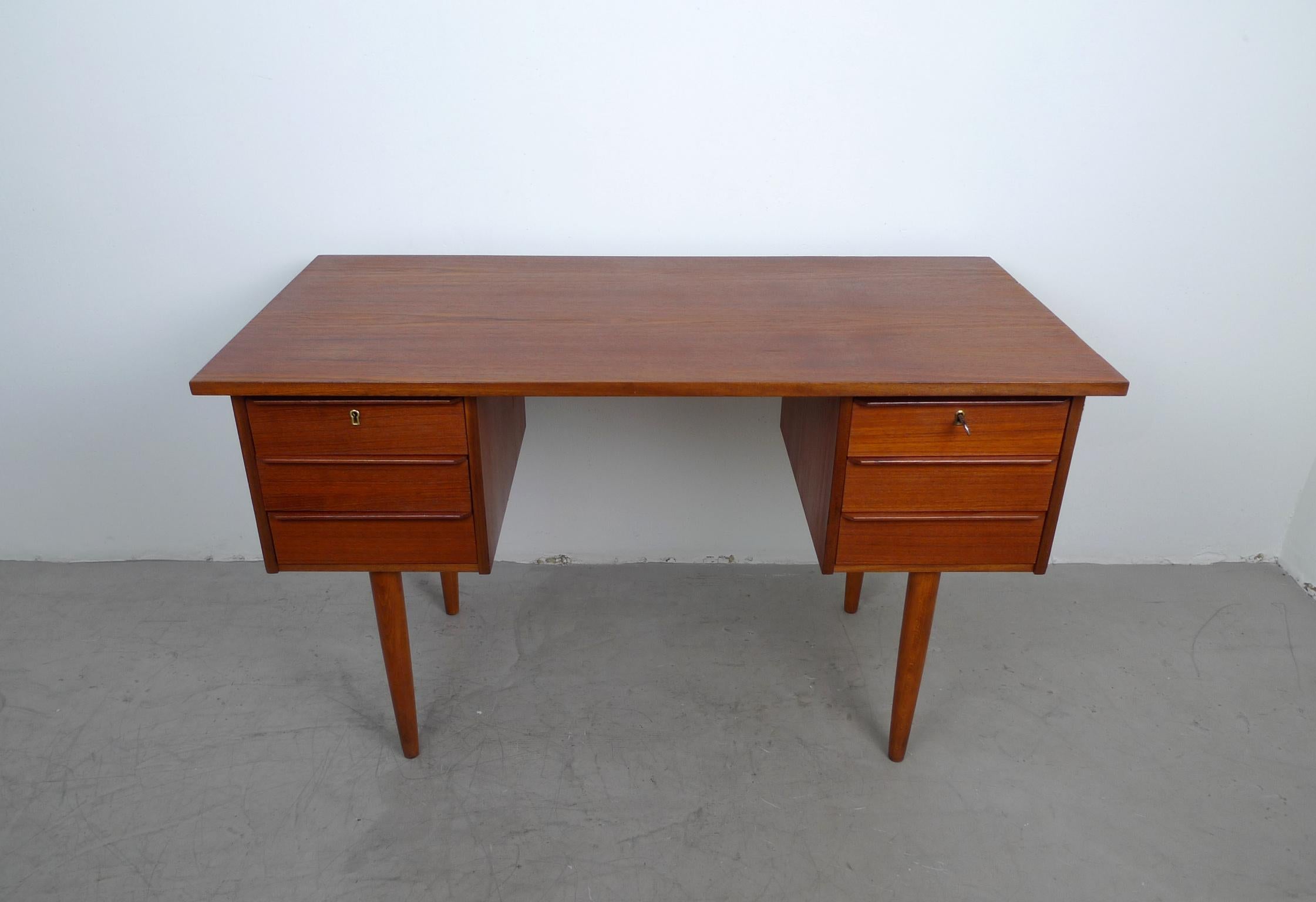 This small teak desk features six drawers. It has two upper drawers that are fitted with a mortise lock. The desk is in very good original condition, only the right side shows one scratch.