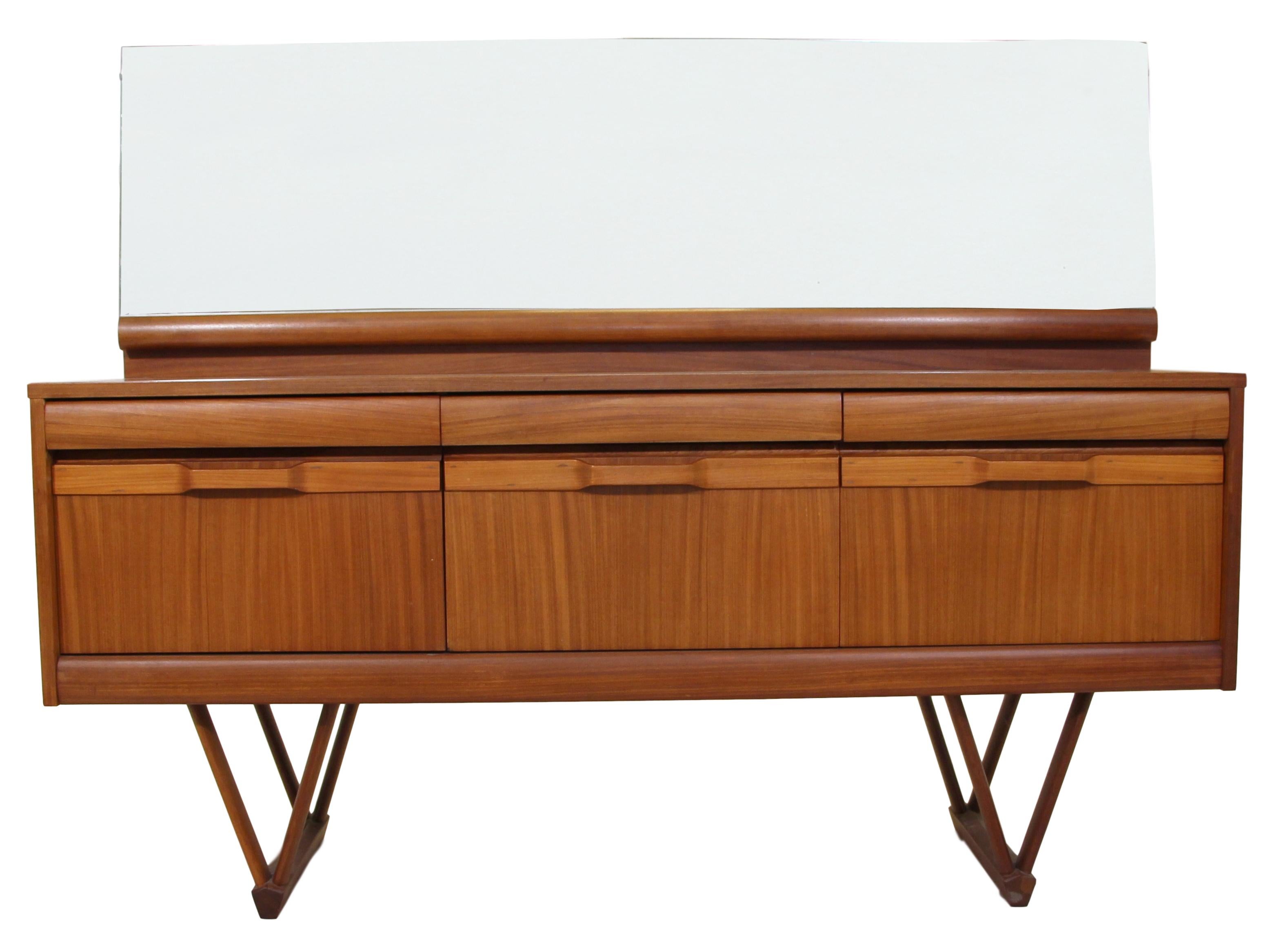 This is an outstanding 1960s teak dresser or credenza with V shaped legs.
Made by Elliots of Newbury. Made in England. 
Featuring 3 large drawers at the bottom and 3 small drawers at the top. Original brown baize in the top middle drawer.

Very