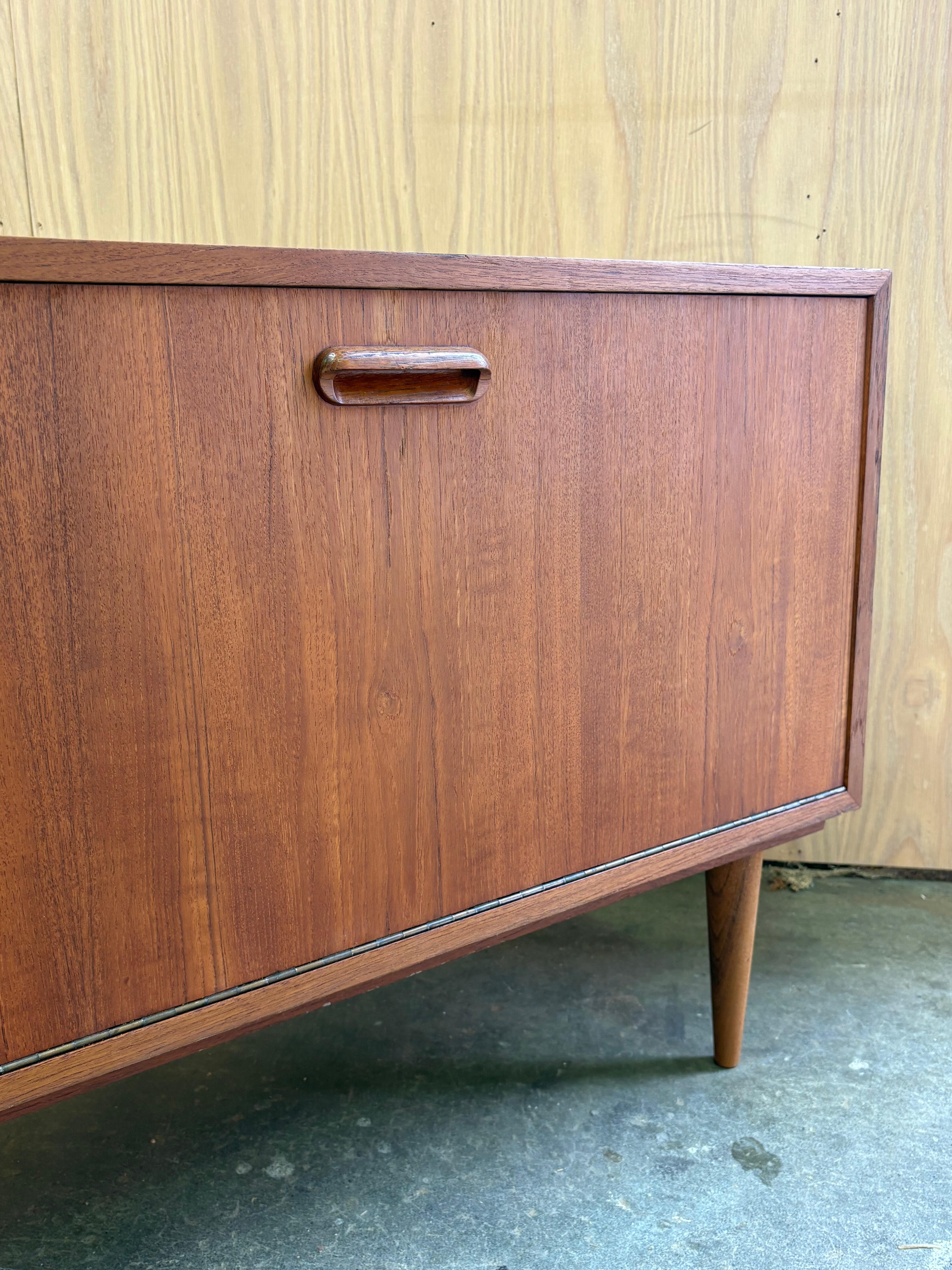 Rare meuble à disques en teck des années 1960, d'une grande beauté, avec une façade rabattable et des séparations intérieures sculptées, parfaitement adapté au rangement des vinyles. Fabriquée au Canada, cette pièce se distingue par son encombrement