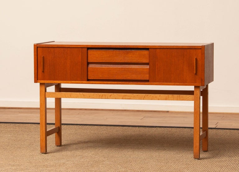 Beautiful small console / Hall cabinet / entry credenzas in teak resting on a beech stand and made in the 1960's in Sweden.
This small cabinet consists two drawers as wel as two sliding doors.
Overall in good condition.