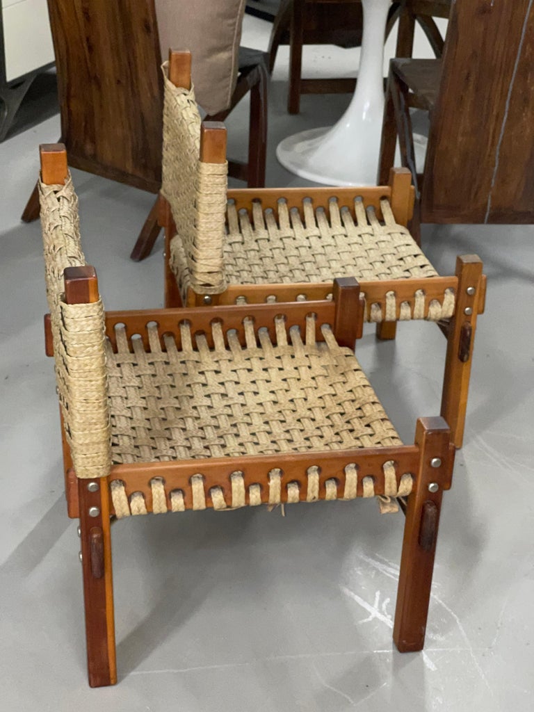 A nice pair of vintage teak and raffia low chairs likely from India in the style of Mini Boga for Tauru. These chairs are low, they are pictured next to a vintage Percival Lafer sofa for scale. The chairs have some wear to the raffia but are sturdy.