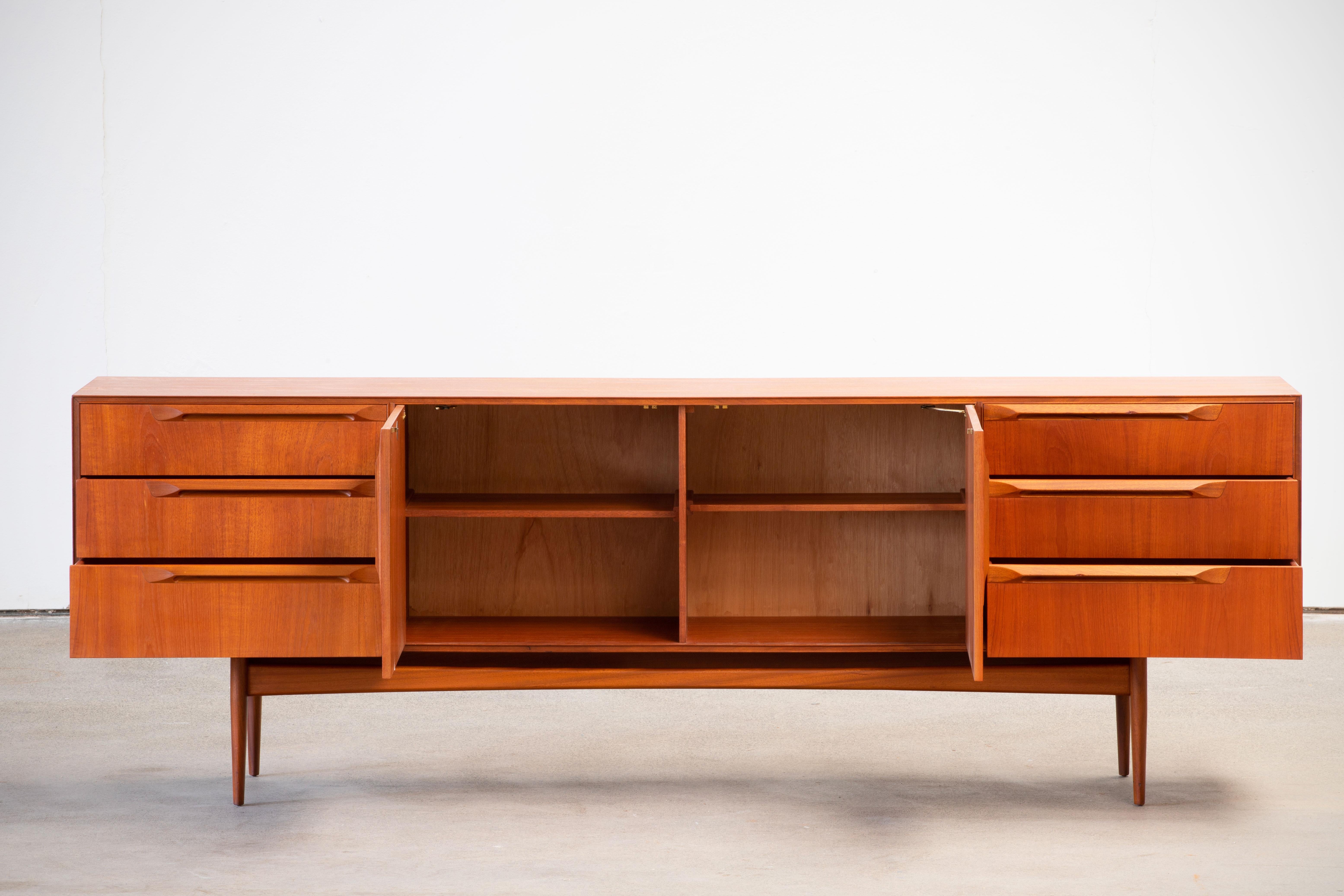 This beautiful vintage modern rosewood sideboard features plenty of room for storage within its six drawers and two large storage compartments hidden by cabinet doors. Sleek two-tone design with unique carved pulls and tapered legs adding to the