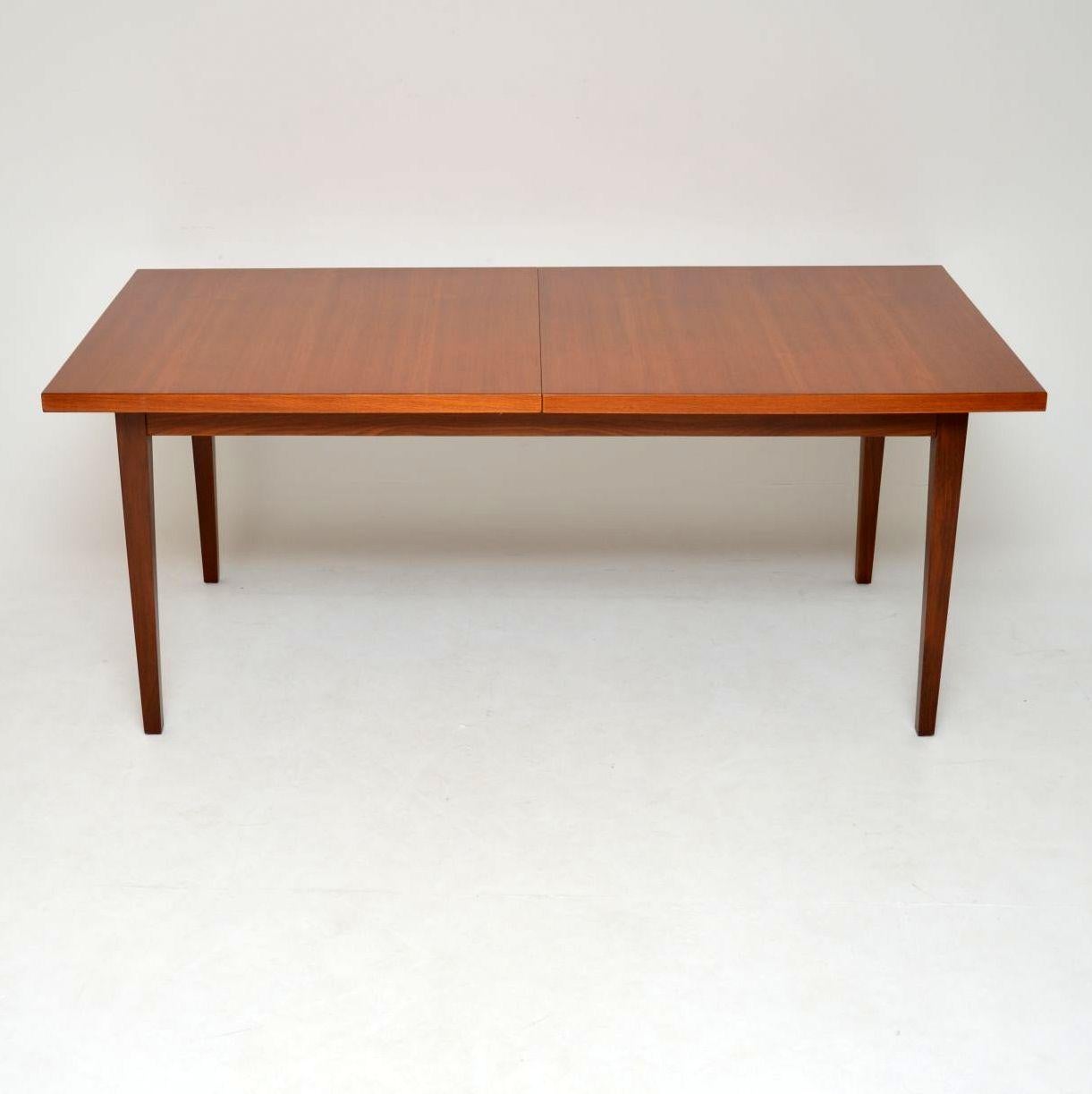 A beautiful and extremely well made vintage teak dining table from the 1960s. This was designed by Robert Heritage for part of the Dorrington dining range, manufactured by Archie Shine. It has a foldaway leaf that is built in and stores beneath the