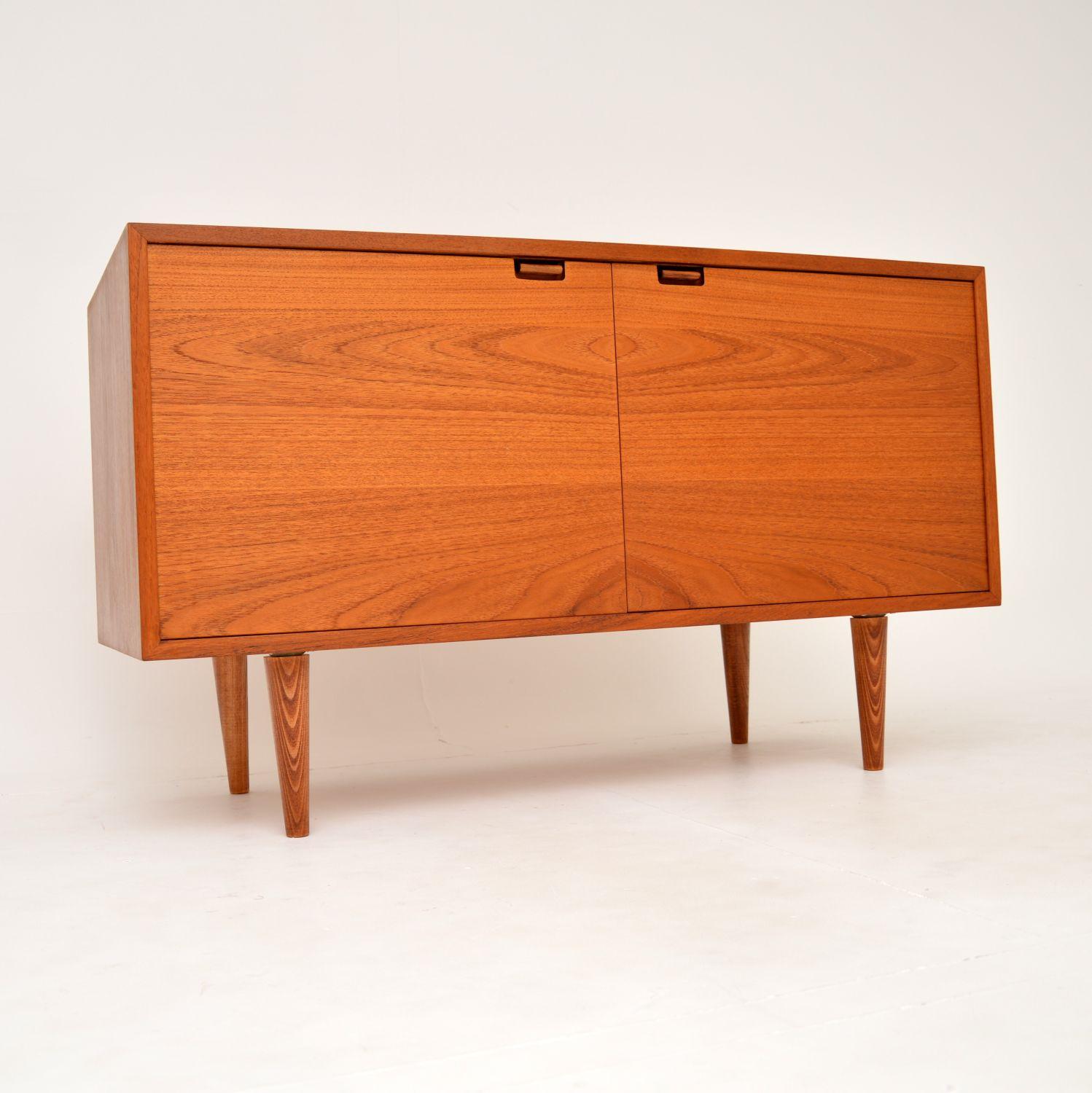 A beautiful and petite Danish teak sideboard on legs. This was made in Denmark, it dates from around the 1960’s.

This is a very useful size, low and not too wide, with plenty of storage space. The handles are rosewood and have a clever mechanism