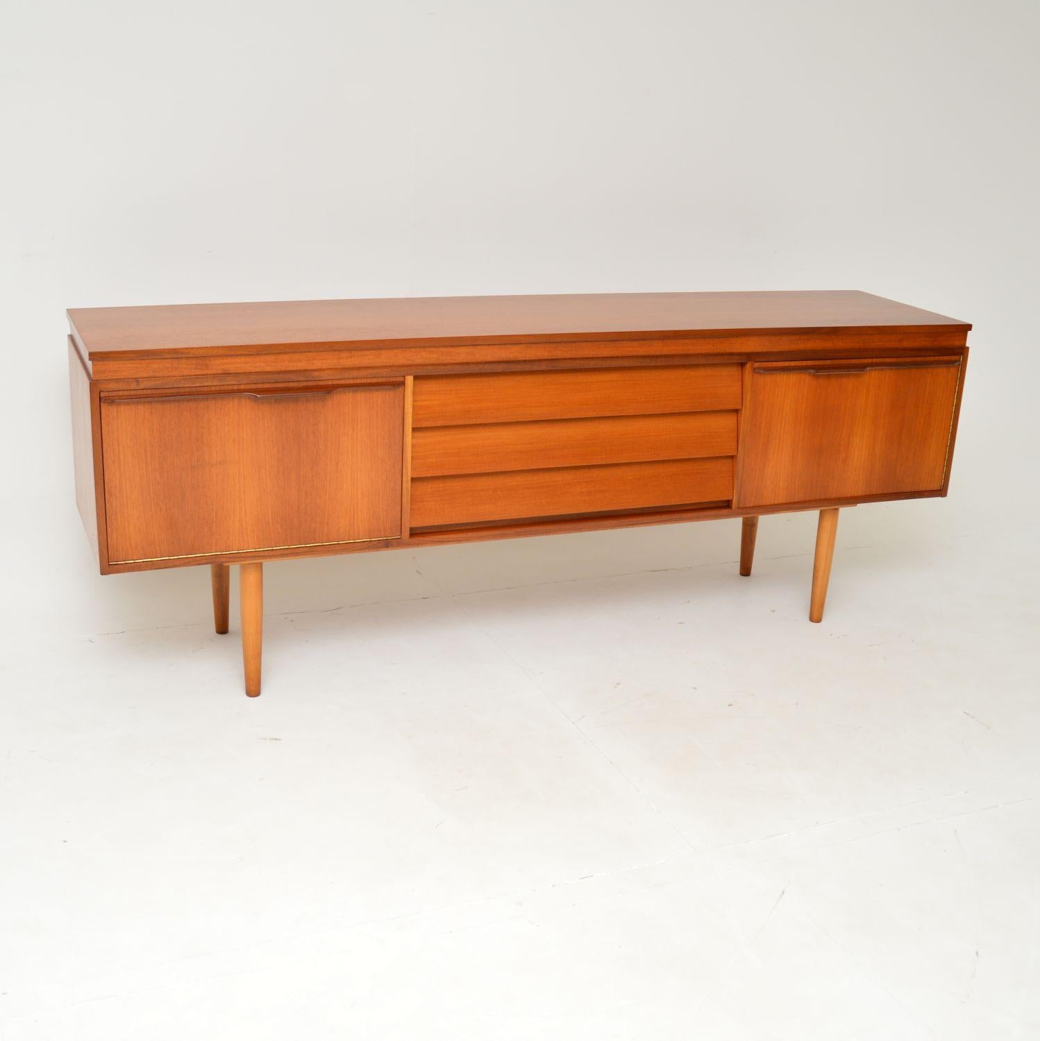 A sleek and very stylish vintage teak sideboard. This was made in England, it dates from the 1960’s.

This model is of superb quality, with two doors either side of three slanted drawers. The doors have beautifully sculpted lipped handles, the left