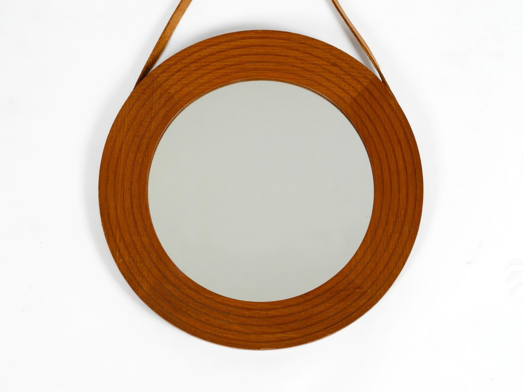 Original 1960s beautiful wall mirror with wide teak frame. The original leather strap for hanging is completely stretched around the mirror.
Very high-quality workmanship in a Minimalist Danish design. 100% original condition and in very good