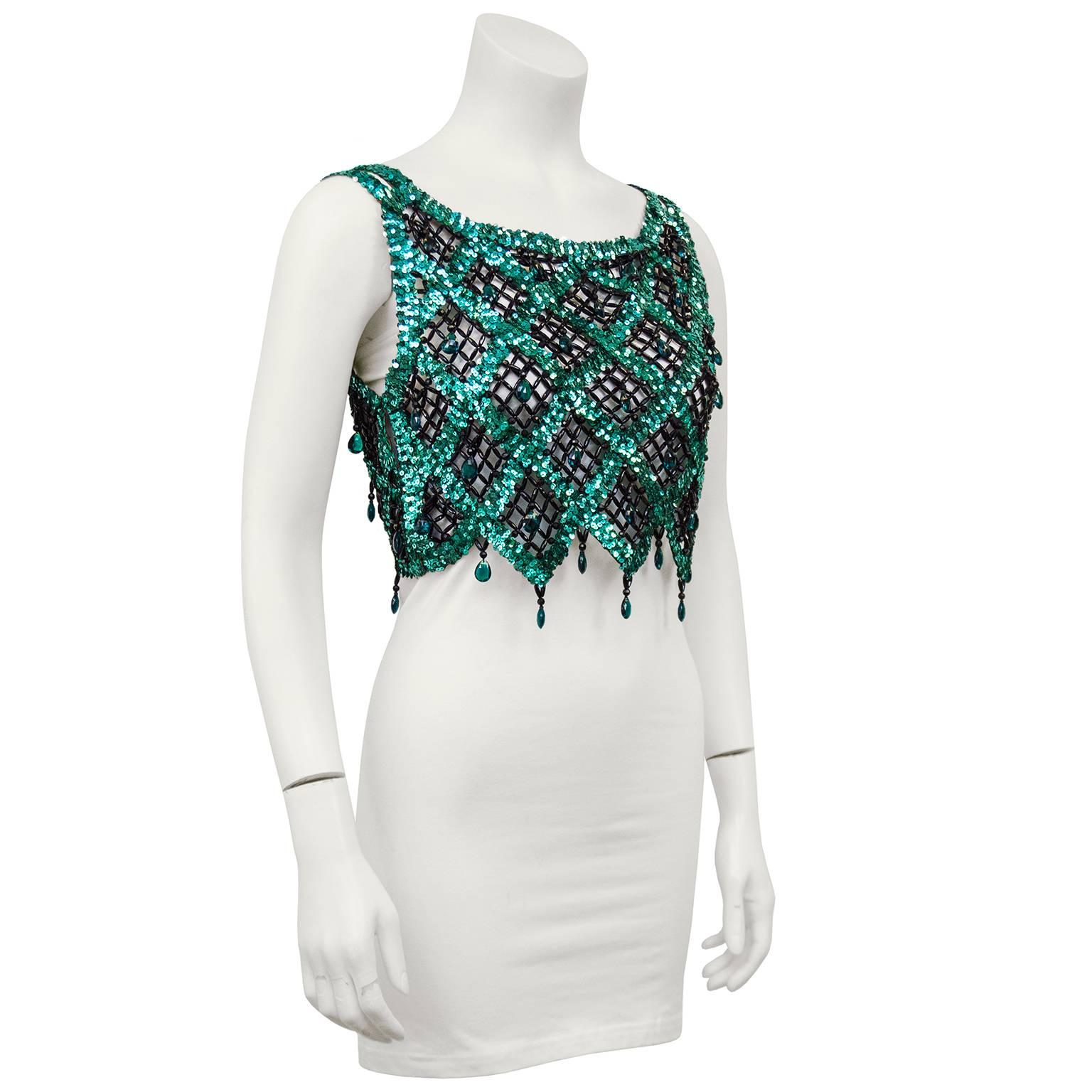 Gorgeous hand detailed 1960s sequin and beaded crop top. Teal sequins in diagonal stripes going both ways, creating diamond shapes throughout with a chevron hem. Small black beads create a net like detail. Large teal teardrop shaped beads in the