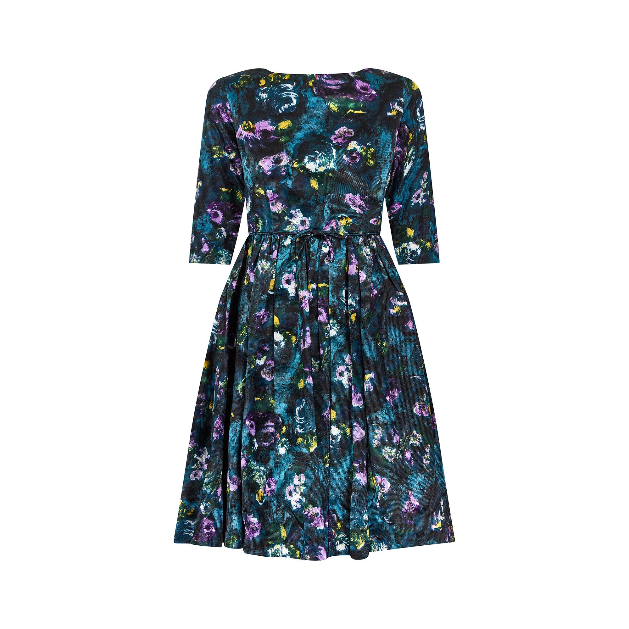 Superb example of an early 1960s day dress but could just as easily be worn in more formal settings or as a cocktail dress. Cut in a beautifully iridescent teal blue silk feel fabric, it has a high, rounded neckline, with three quarter length