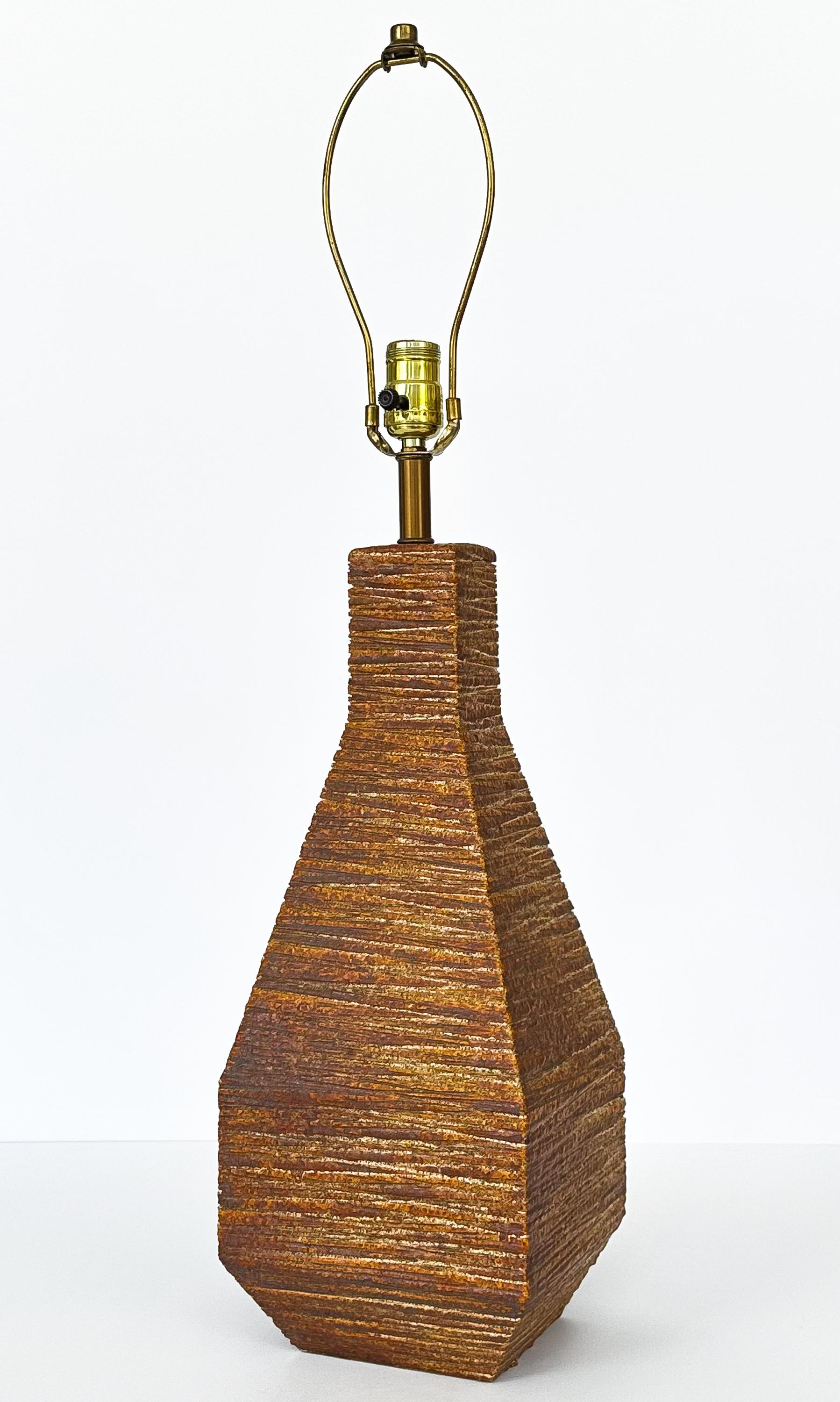 Cette étonnante lampe de table en céramique texturée des années 1960 incarne l'essence du design moderne du milieu du siècle avec sa forme géométrique unique et sa glaçure profonde et richement colorée. Le corps de la lampe est une étude de texture