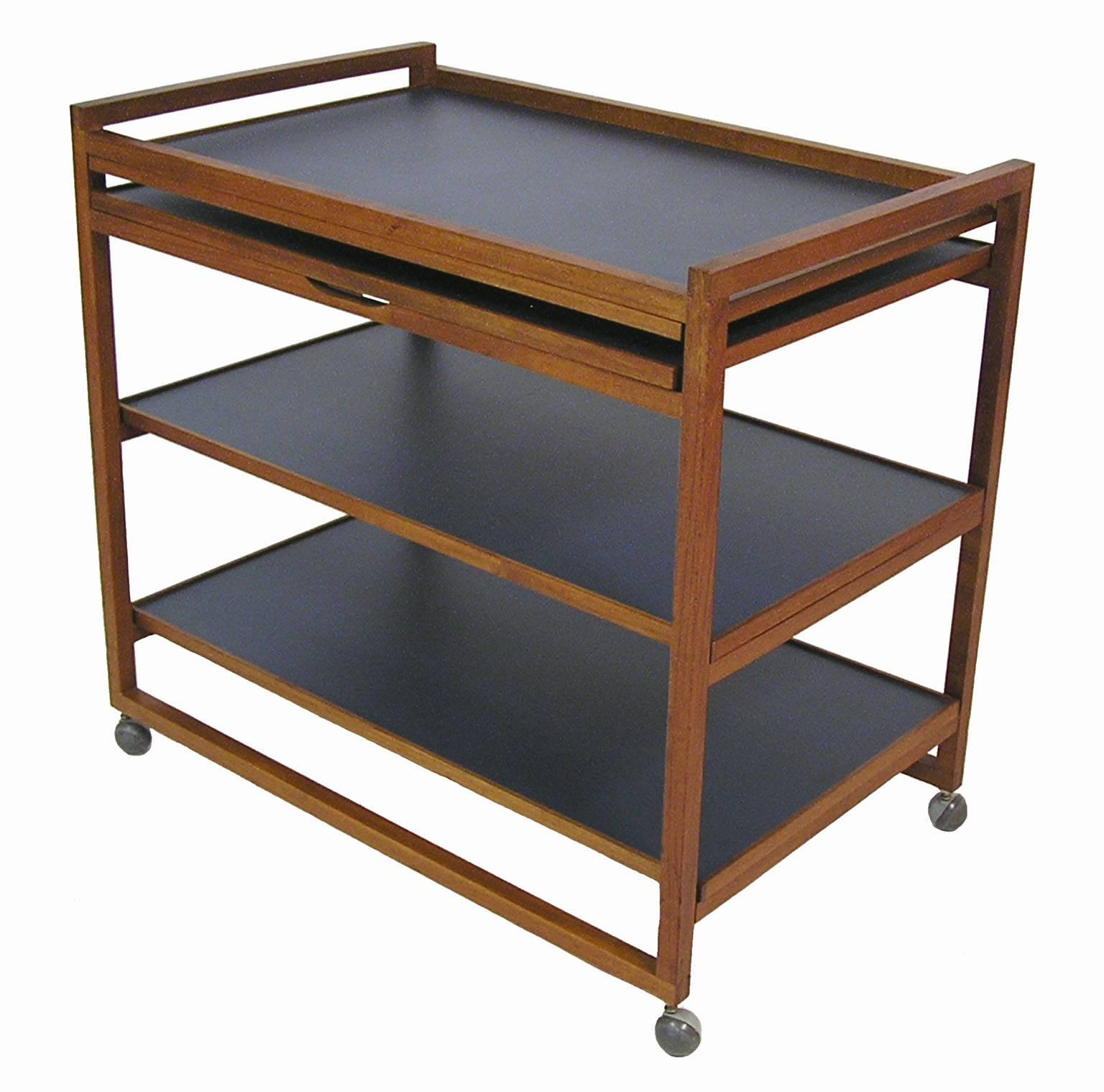 A unique three-tier teak and Laminate serving/bar cart from the 1960s Danish Modern era. Clean Scandinavian Modern era lines with a finger jointed solid teak frame, original castors and multiple laminated surface areas that are each designed to
