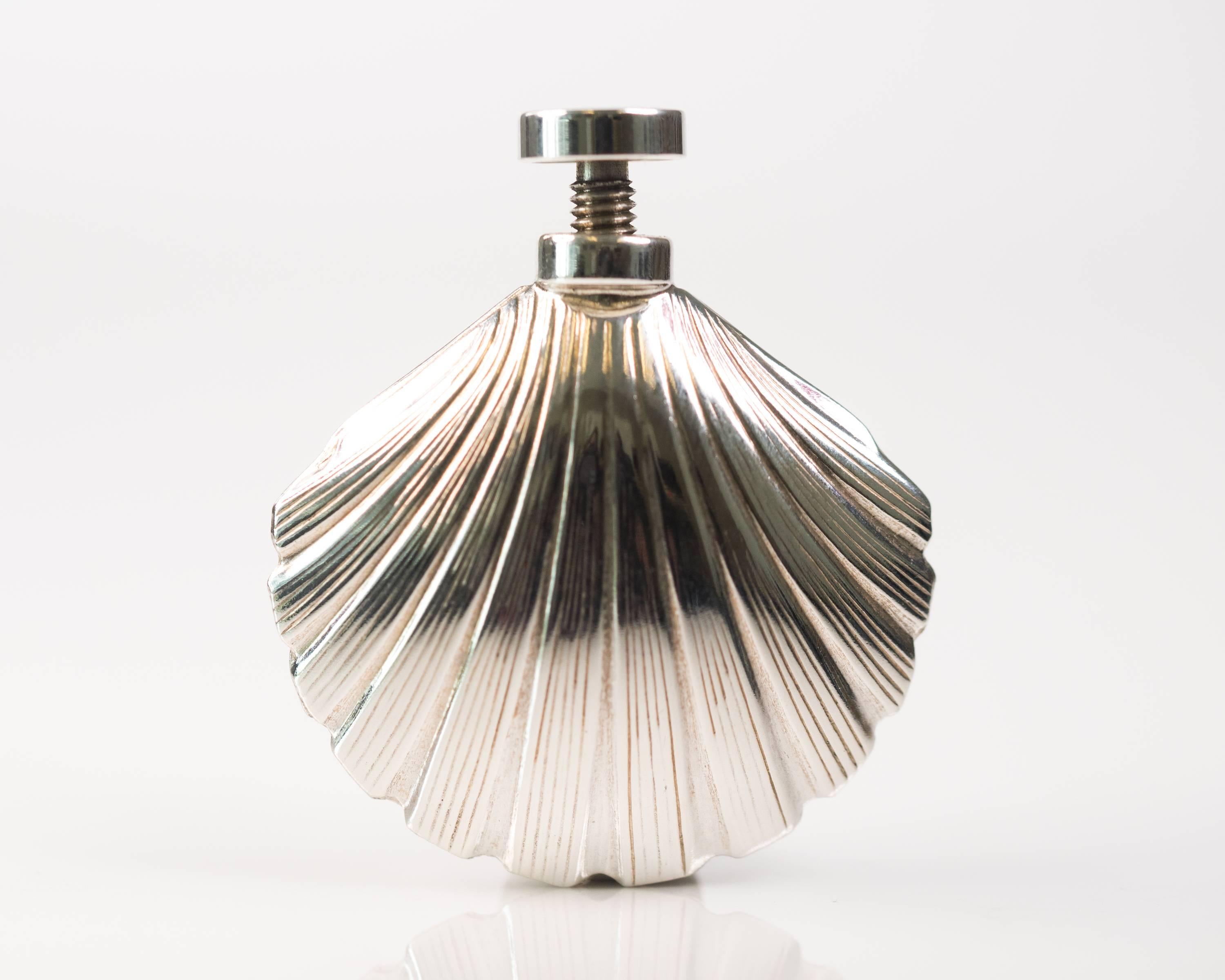 1960s Tiffany and Co Sterling Silver Scallop Sea Shell Perfume Bottle

Features a sterling silver dauber with threaded end cap which screws securely into the bottle. The Sterling Silver bottle is in the shape of a scallop sea shell. The shell is