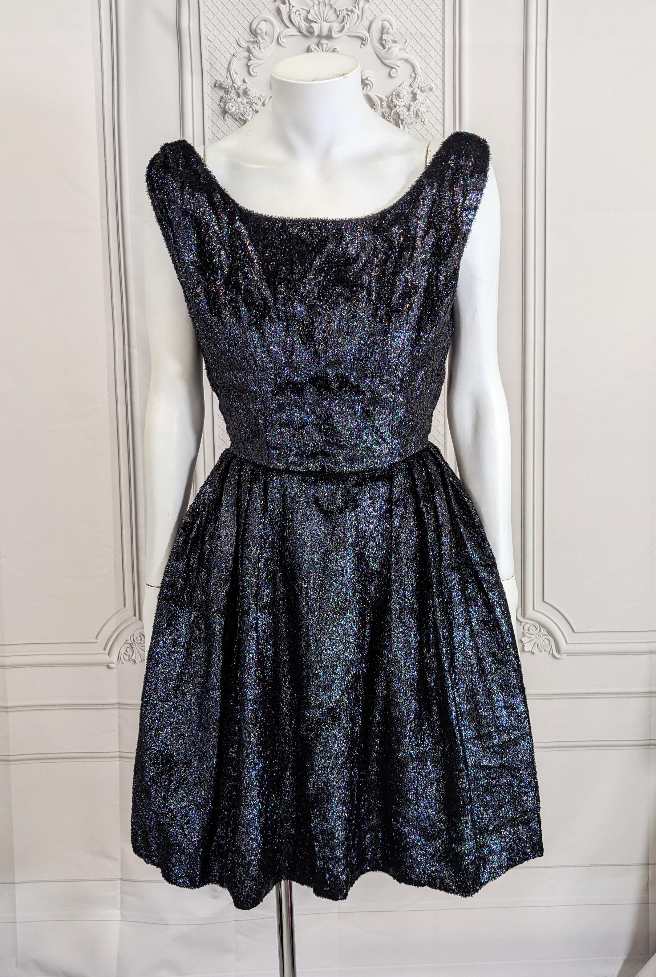 Charming iridescent tinsel velvet cocktail dress from the 1960's. Straps sit wide on shoulders with tiny pinched waist and full pleated skirt.  Back zip entry with 2 long ties which add interest on the back.
Textile is shiny black tinsel velvet with