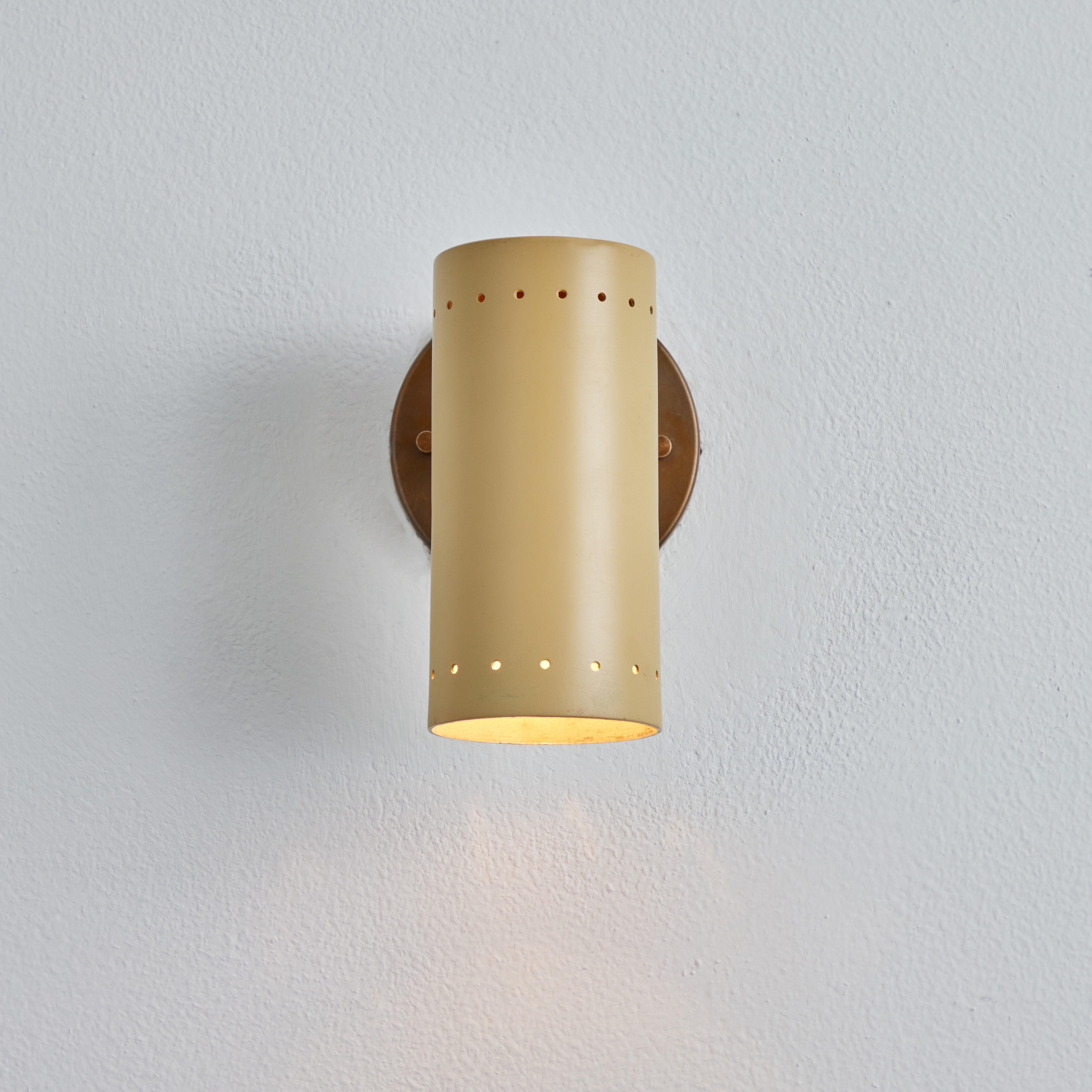1960s Tito Agnoli beige metal and brass articulating sconce for o-luce. One of his most highly refined minimalist designs. Sleek and functional yet at the same time bright and playful. A highly adjustable wall light, the tubular shade rotates freely