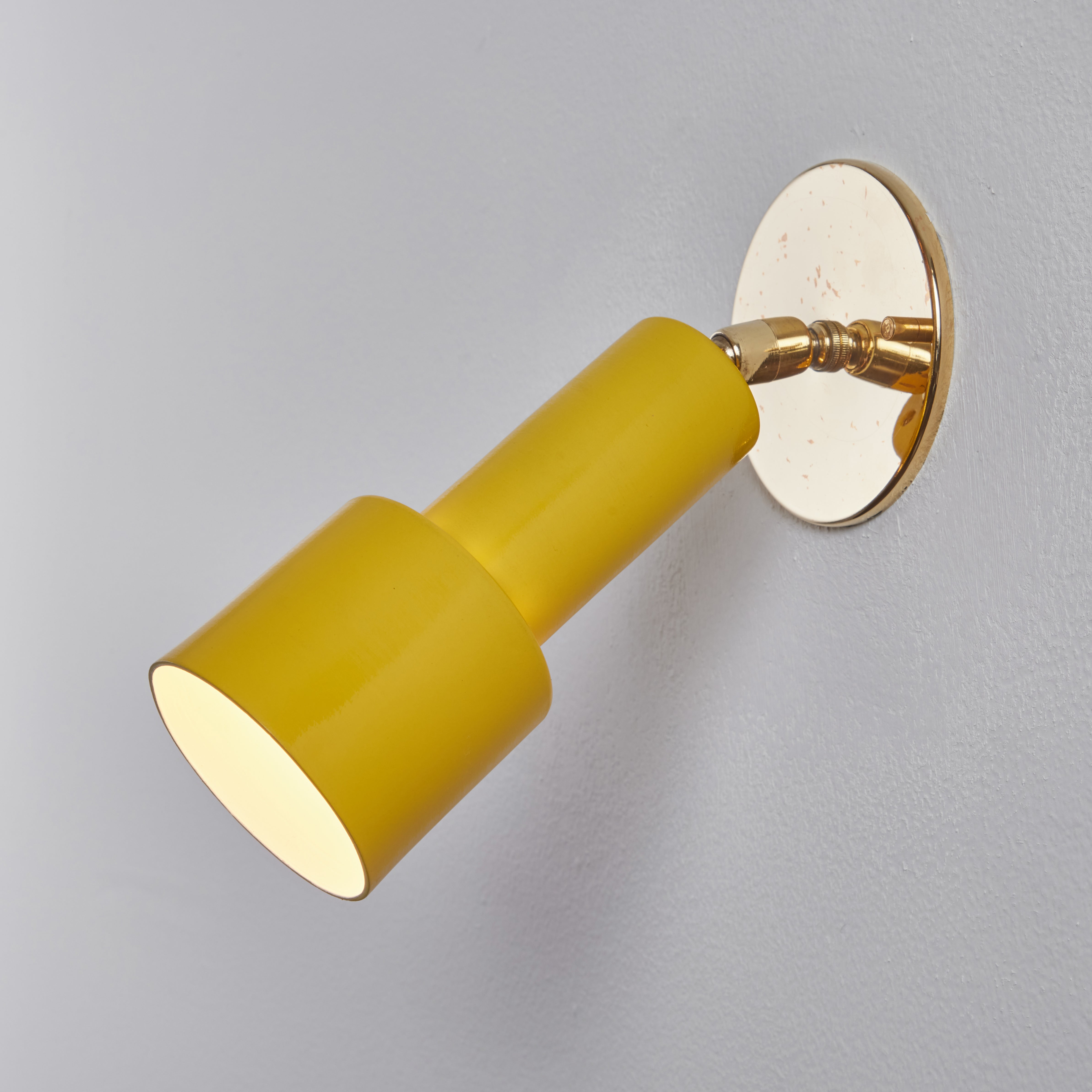 1960s Tito Agnoli perforated yellow metal & brass sconce for O-Luce. These iconic sconces are executed in yellow painted perforated metal and brass. Lamps rotate freely on highly adjustable double swivels. An incredibly clean and refined design by