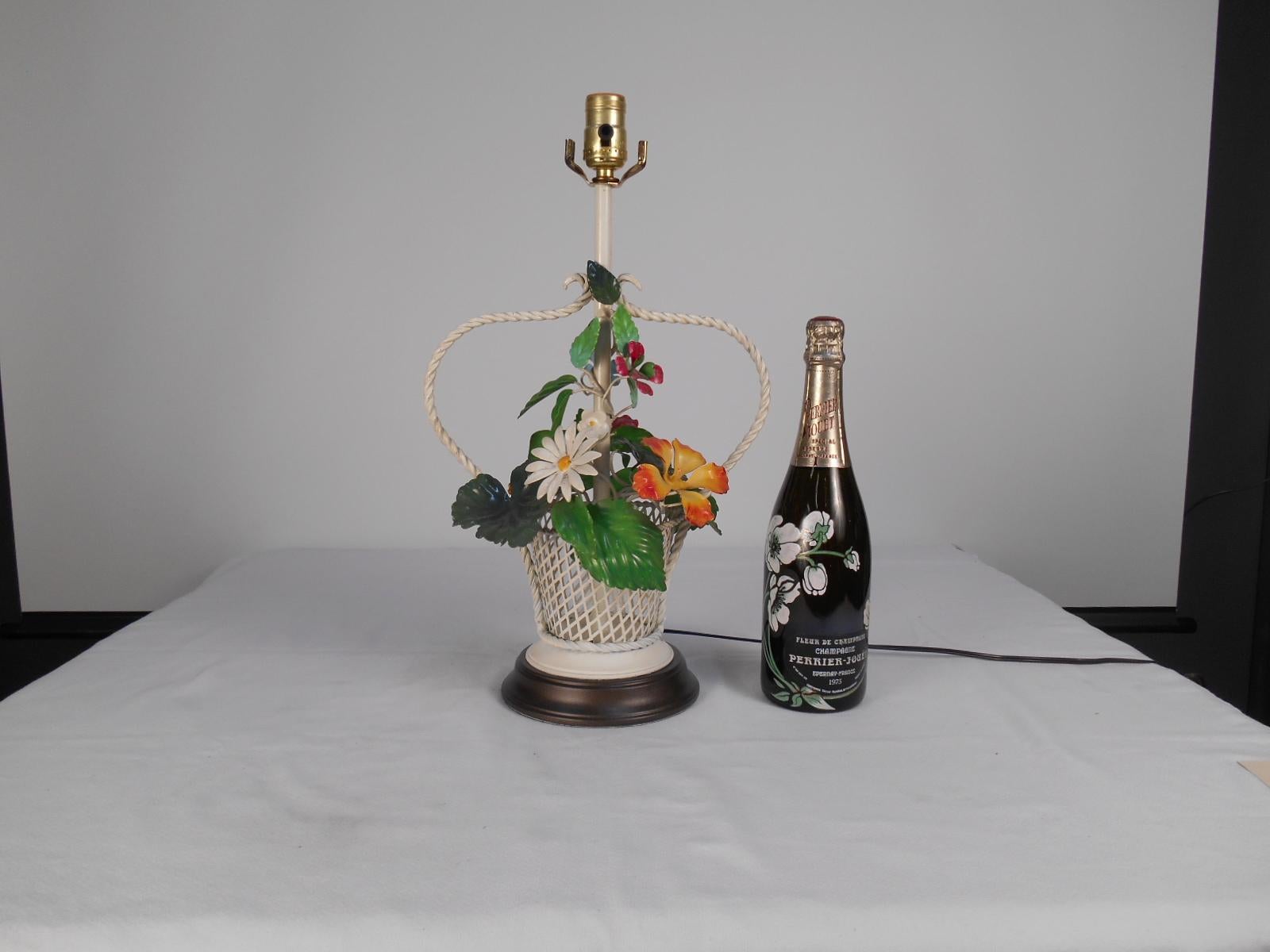 A charming colorful tole floral basket table lamp. Made in the 1960s. The white painted basket off sets the greens, oranges, reds and yellows withing the tole floral bouquet. We have freshened up the original lamp base with new paint.