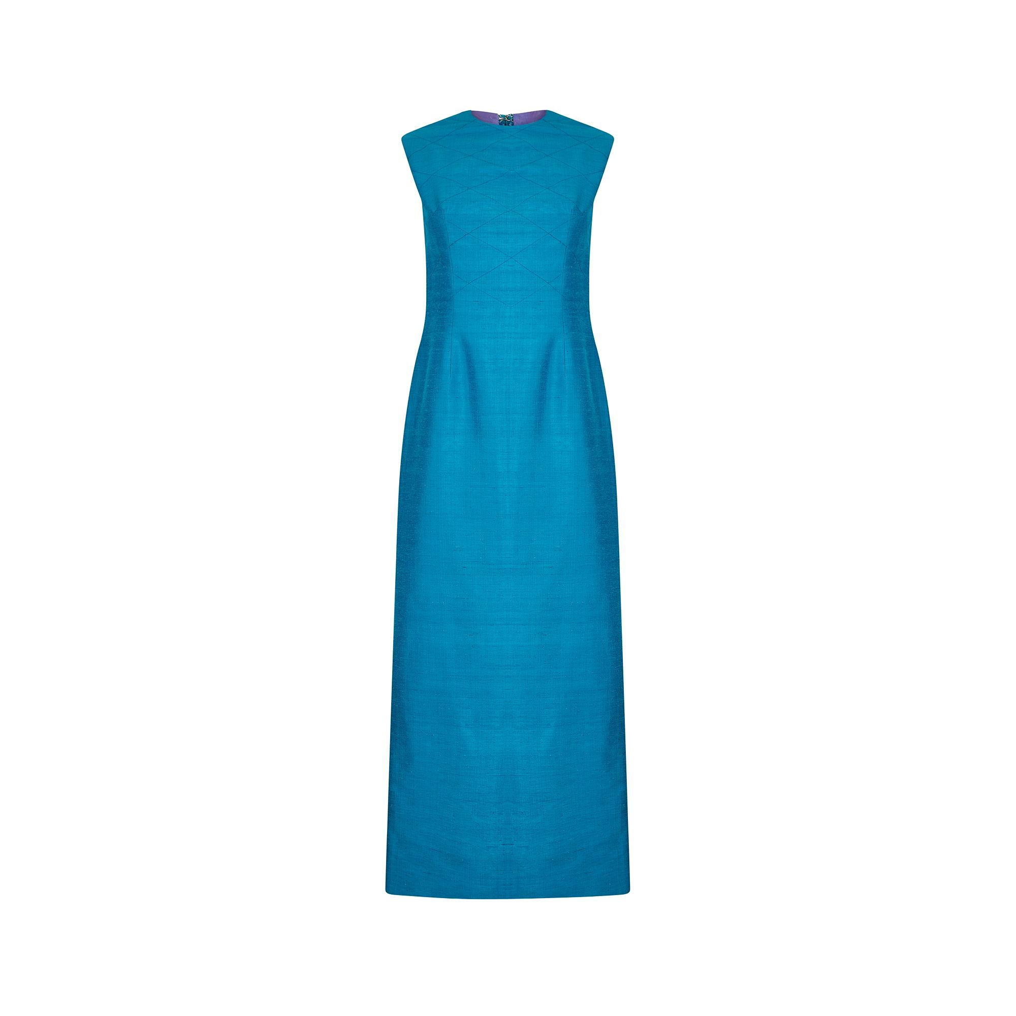 This 1960s Tony Armstrong evening dress is cut in a classic and flattering column silhouette with a high rounded neckline and short, slightly capped sleeves. The front is very lightly embroidered with fine blue thread in a criss-cross pattern.  This