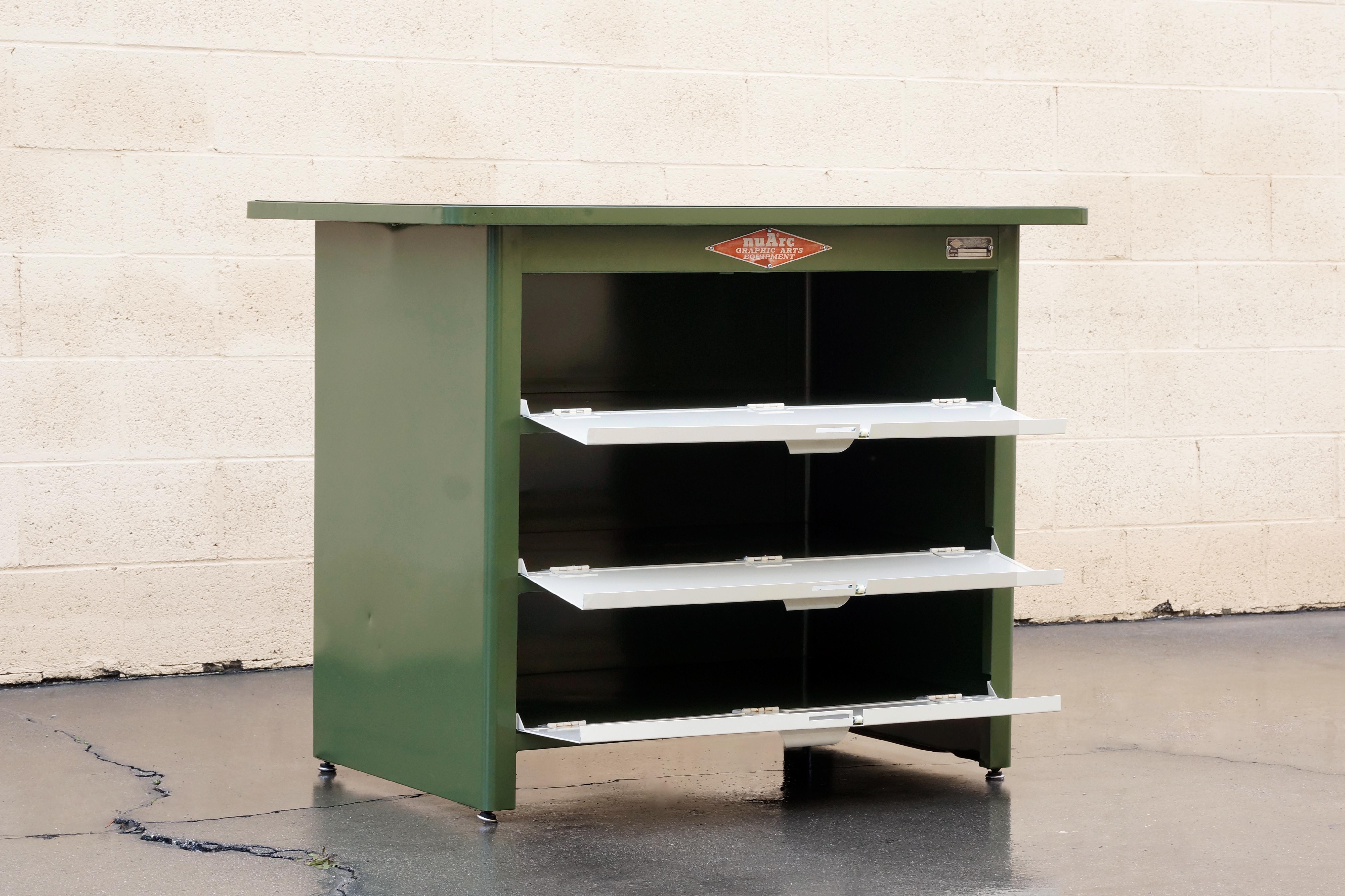 Excellent 1960s tool cabinet meets drafting table by Nuarc Graphic Arts Equipment. We refinished this beauty in two-tone Army Green (RAL6009) and Pearl. Features three doored-shelves and original labels. Looks great in a studio, office, workshop or