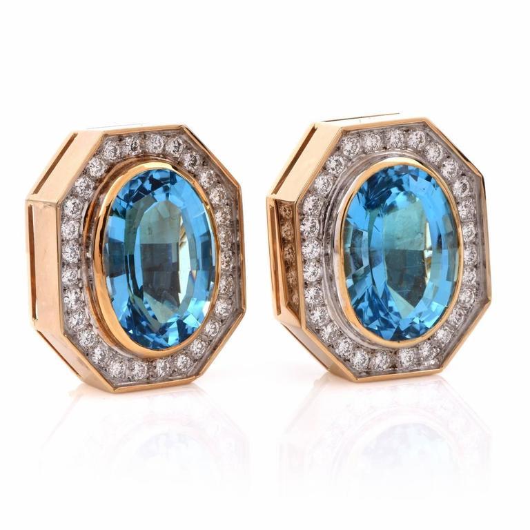 These large 1980's  earrings are handcrafted in solid 18K yellow gold. The earrings are enriched with a pair of highly translucent, oval-faceted blue topaz, cumulatively weighing approx. 37.00cts, mounted within yellow gold. The enchanting blue