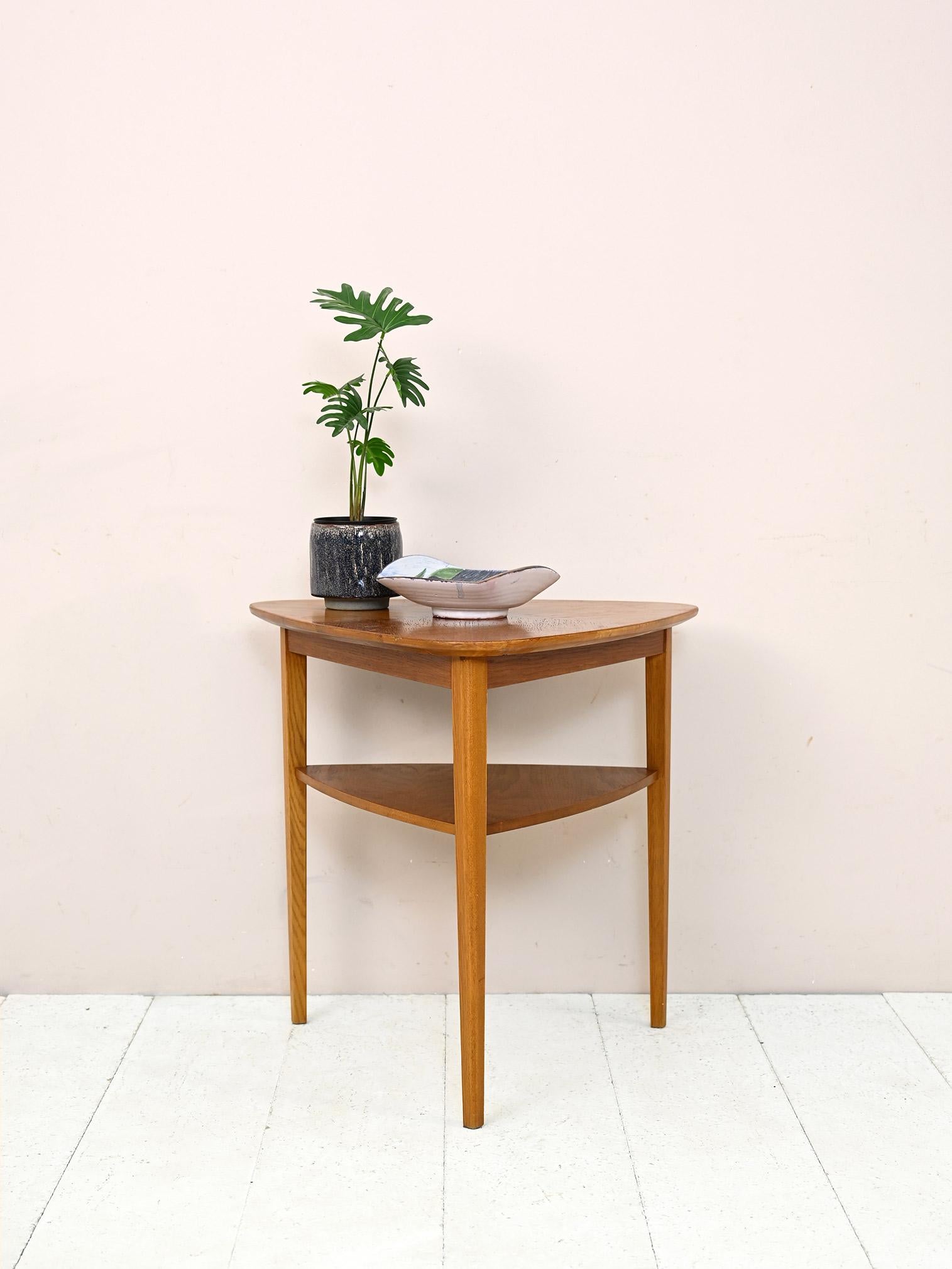 Scandinavian coffee table with double shelf.

This piece of furniture made distinctive by its triangular shape features a table top with rounded corners and long tapered legs.
The light color of the wood and minimal lines make it a modern object