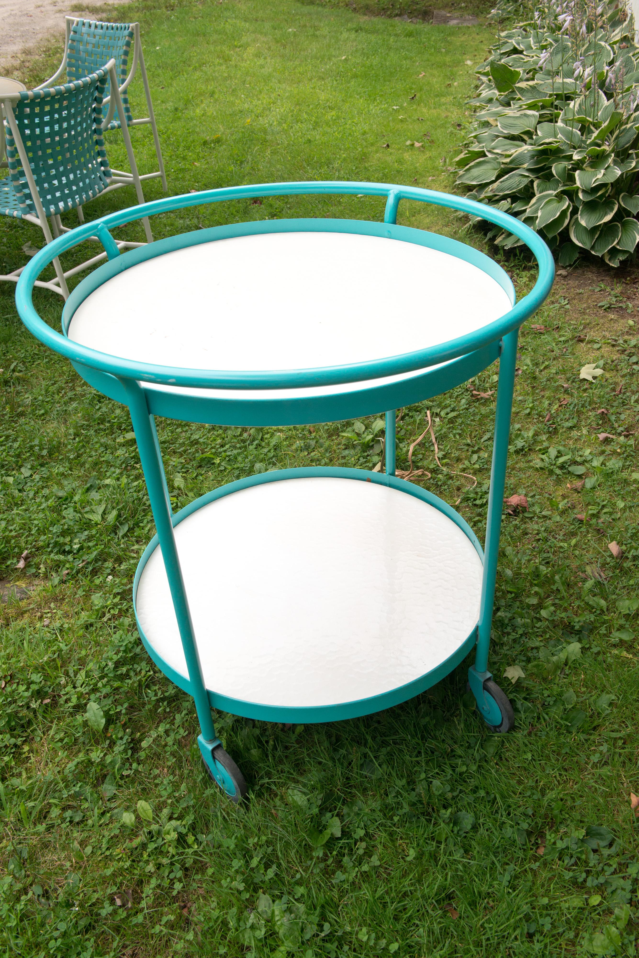 1960s Tropitone turquoise powdered coated aluminum round cart with two white laminate surfaces. Other separately priced pieces to this set: Stunning table & 4 turquoise vinyl webbed chairs with outstanding multi colored canvas umbrella, turquoise