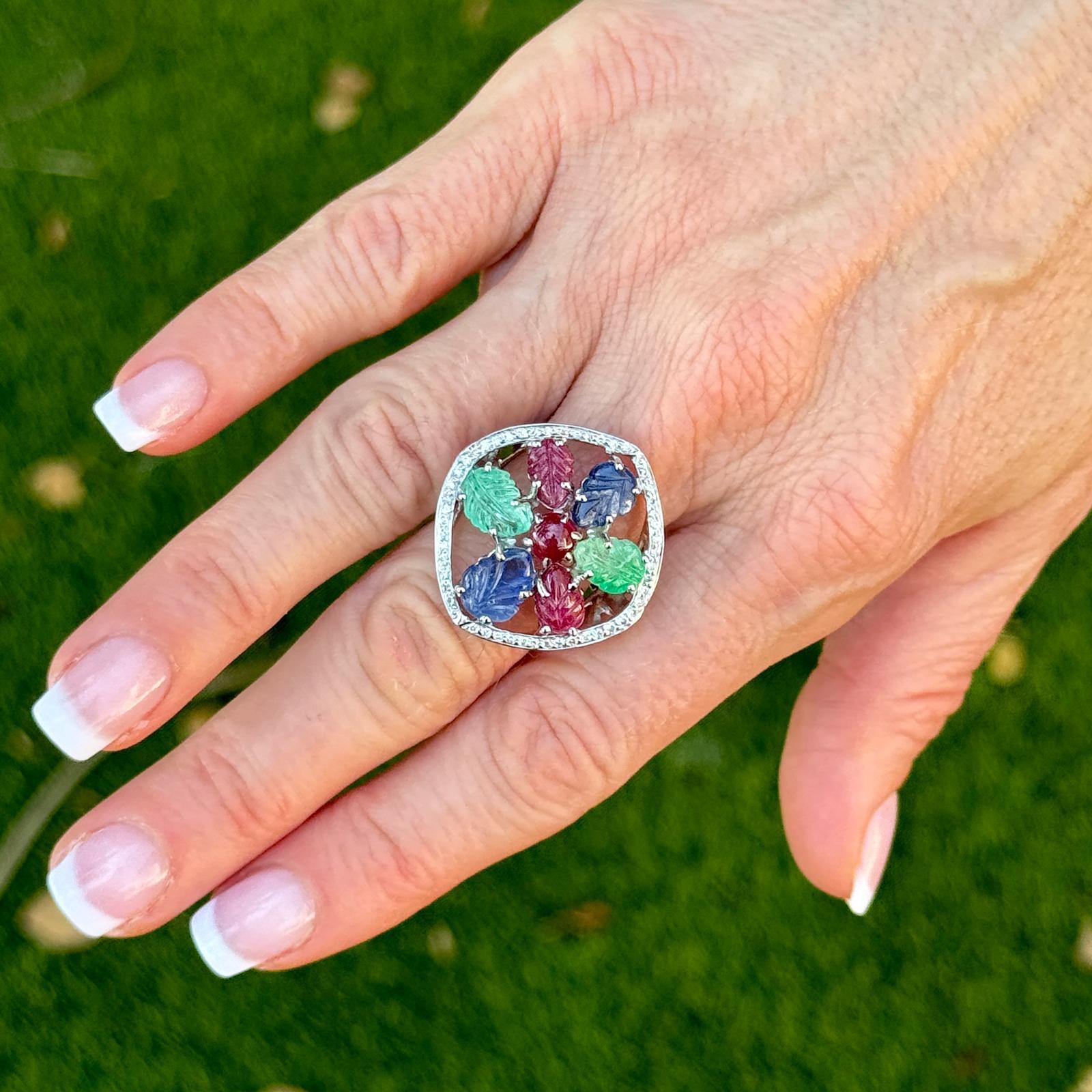The 18k white gold tutti frutti diamond sapphire ruby emerald cocktail ring is a dazzling statement piece that combines luxurious materials with a vibrant array of gemstones. Its bold design, exquisite craftsmanship, and vibrant carved gemstones