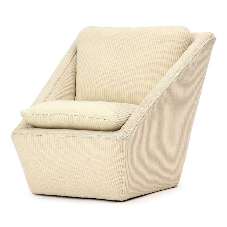An unusual and dramatically angled upholstered lounge chair that retains its original cream corduroy upholstery, the lines of which further accentuate the chair's shape.