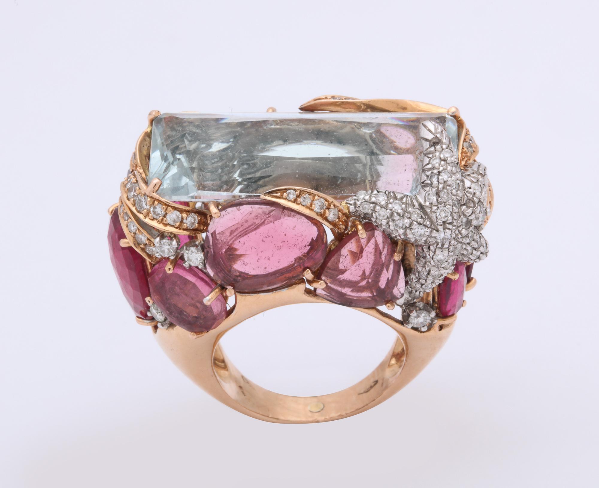 One Ladies !8kt High Polish Yellow Gold Large Cocktail Ring Centering A Unique Rectangular Set Scissor Cut Aquamarine Stone Measuring 25MM.Ring Is Further Designed With A Fabulous Setting Encrusted With Numerous Rubelite,Pink Tourmaline Stones W
And