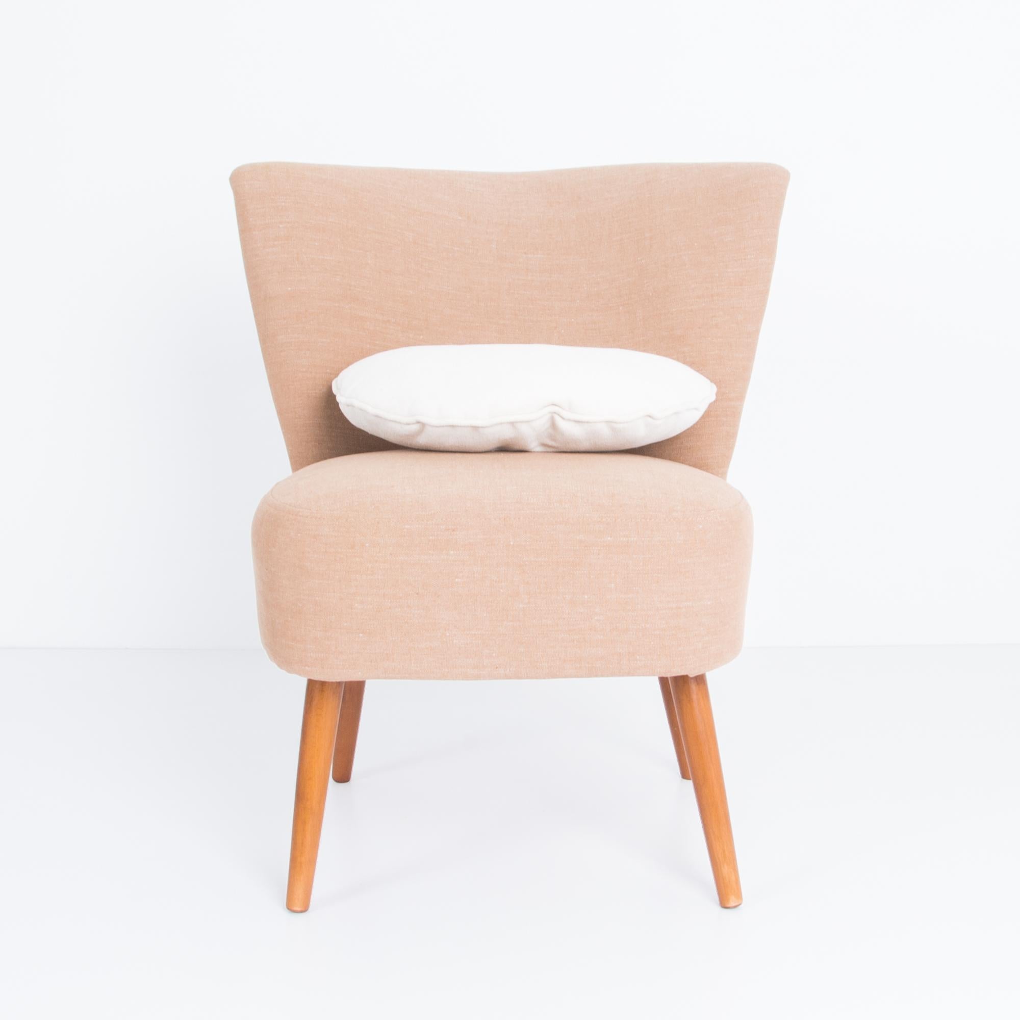 A Mid-Century Modern upholstered side chair from France. This 1960s vintage design has a gentle geometric motif. The chic tapered seat back gives a bold motif, balanced by angled wooden legs. Updated cotton-linen upholstery in a warm peachy hue,
