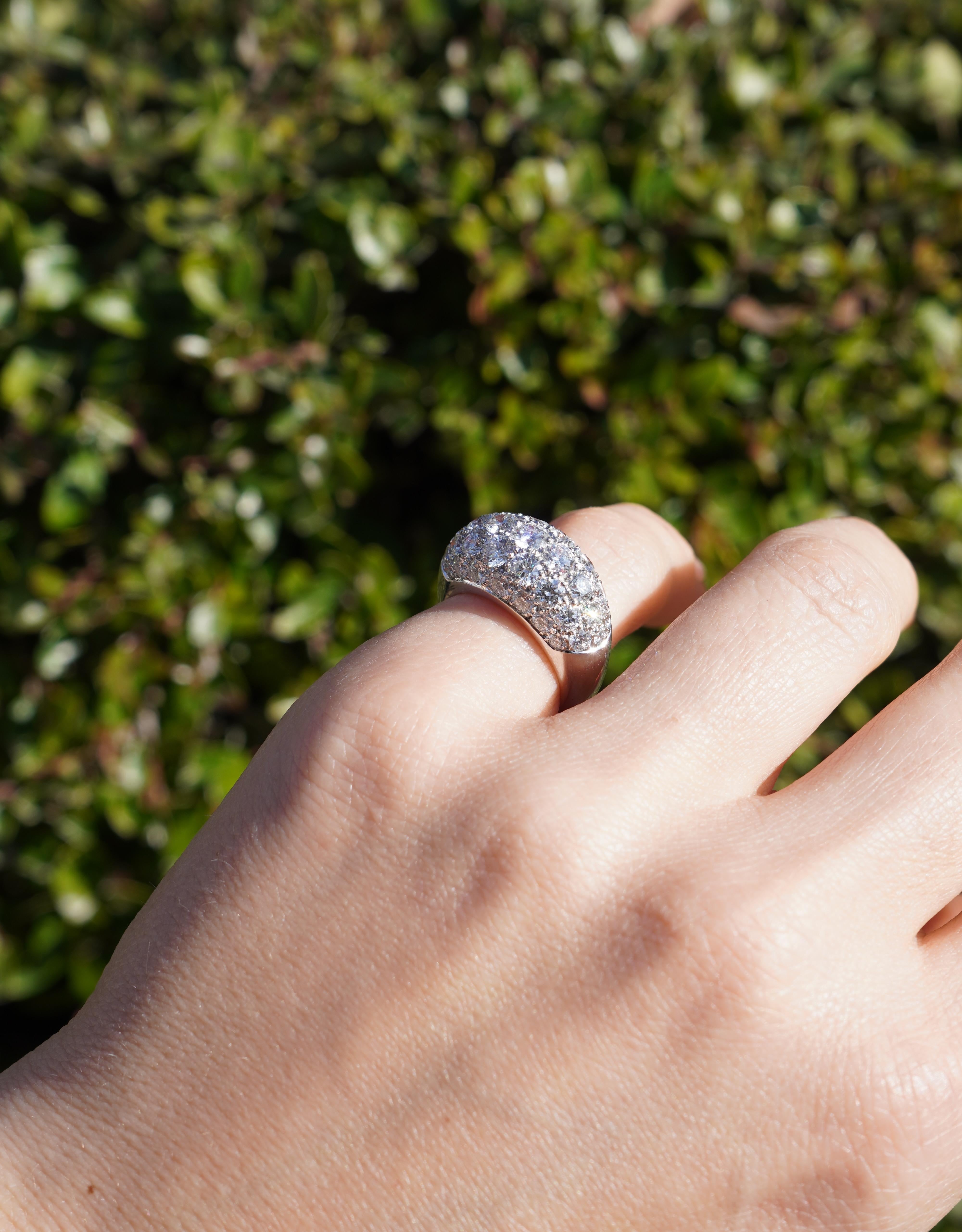 This Van Cleef & Arpels ring from the 1960s is crafted in 18k white gold and features a bombe dome design. The surface is covered in a pave setting of round brilliant-cut diamonds, arranged in a structured pattern that enhances their brilliance. The